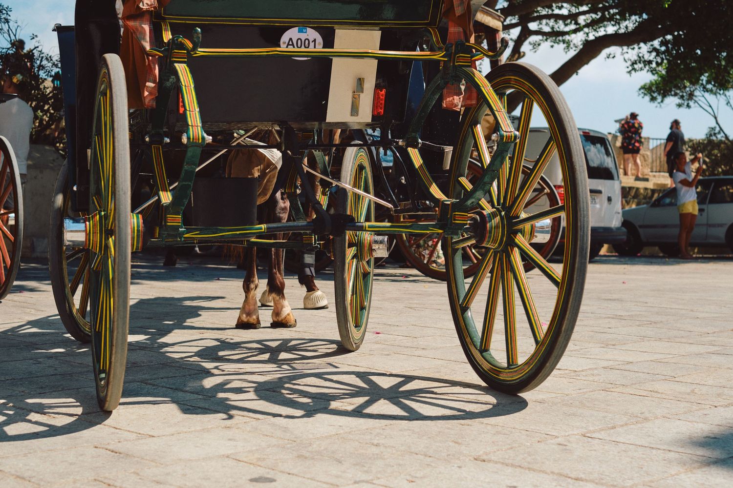 Vintage horse carriage with yellow wheels on stone pavement.