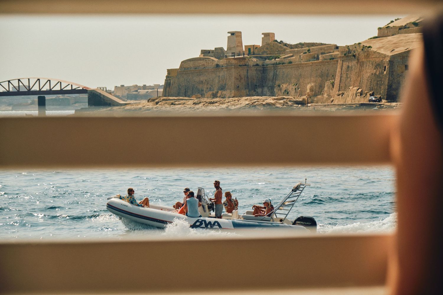 Speed boat carrying passengers along Malta's historic harbor walls and fortifications.