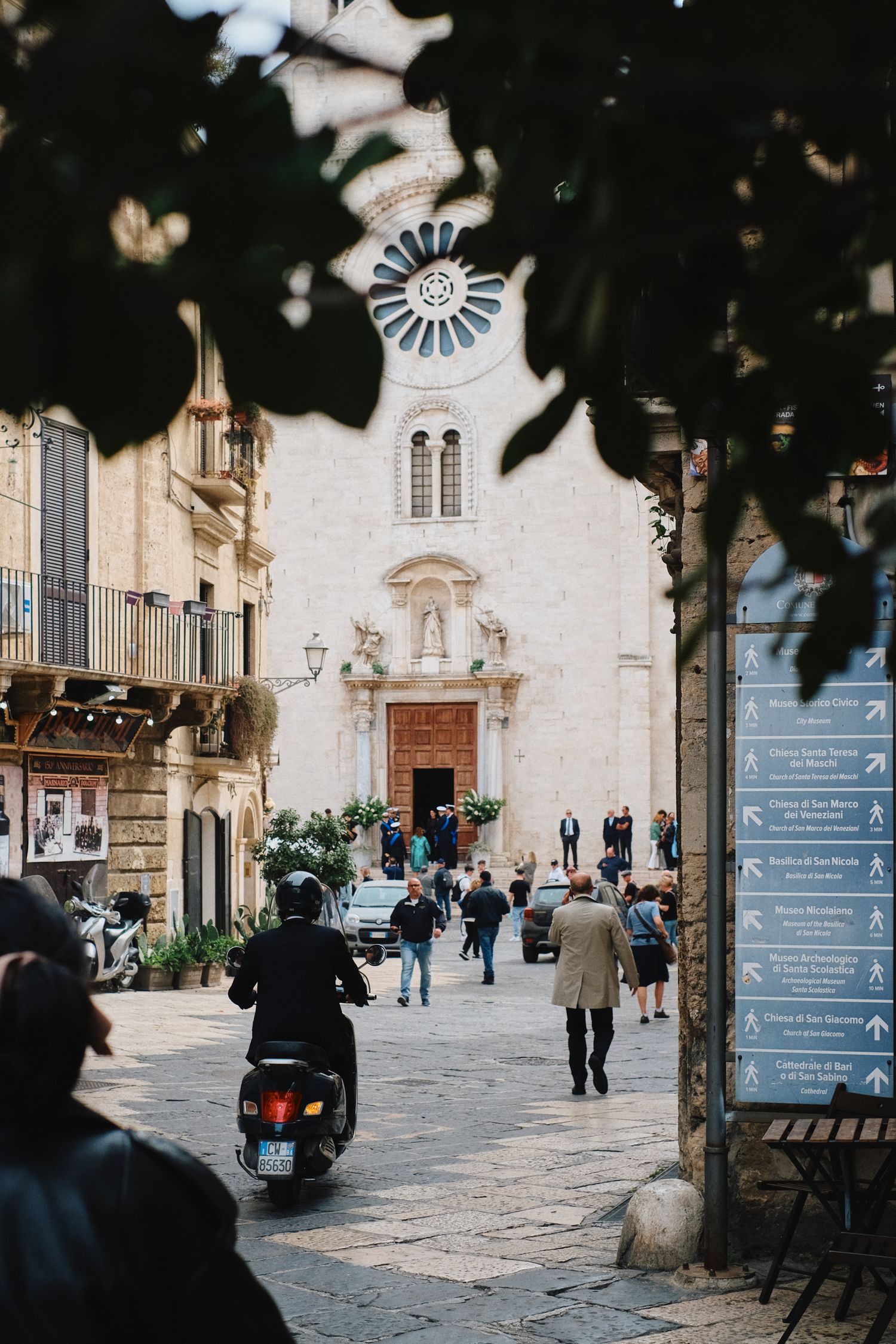 Historic church facade with ornate windows and people walking through a charming European street.
