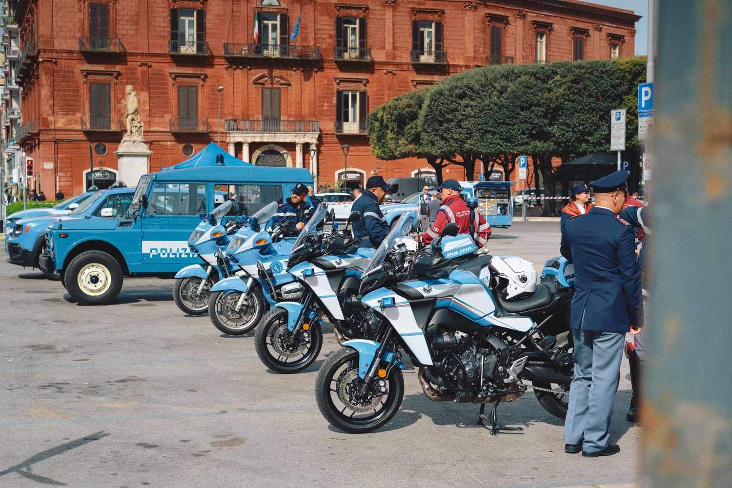 Police motorcycles and vehicles lined up in front of red brick building.
