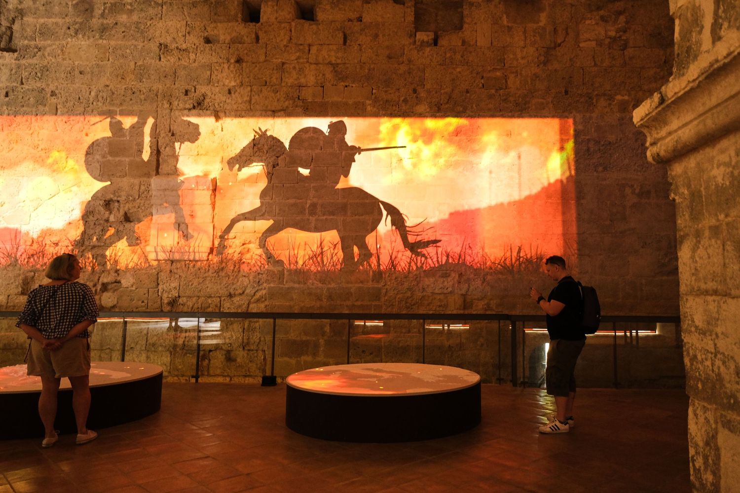 Dramatic backlit mural showing silhouetted figures against an orange background in historic space.