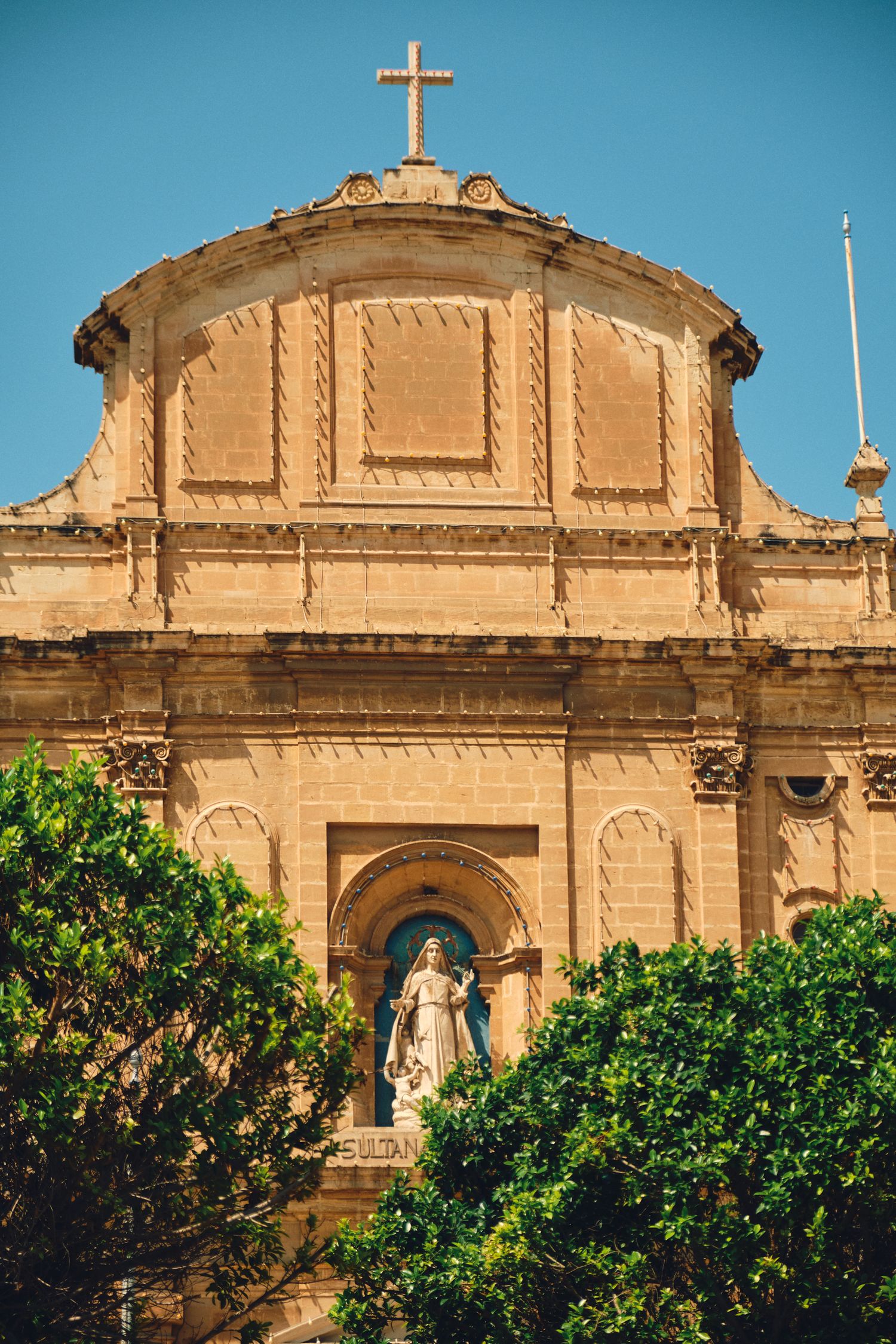 Historic Maltese church facade with ornate architecture and religious statue.