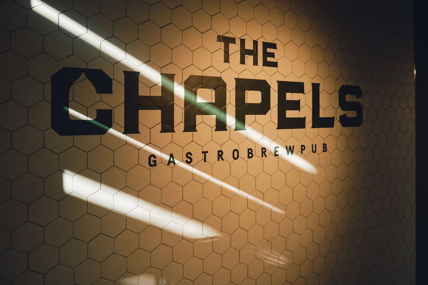 Modern restaurant sign reading 'The Chapels Gastropub' on hexagonal wall pattern.