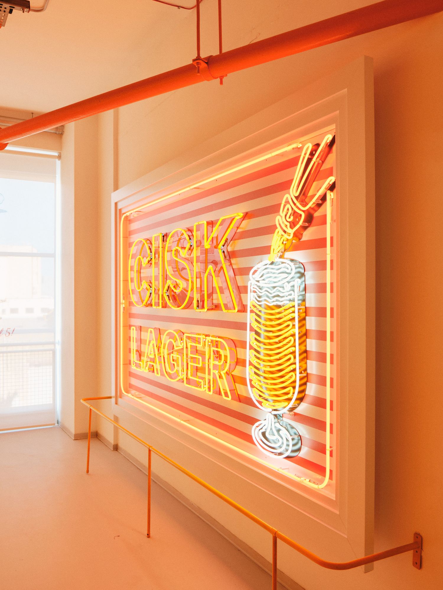 Vintage neon sign advertising Pilsk Lager beer with glowing yellow and orange stripes.