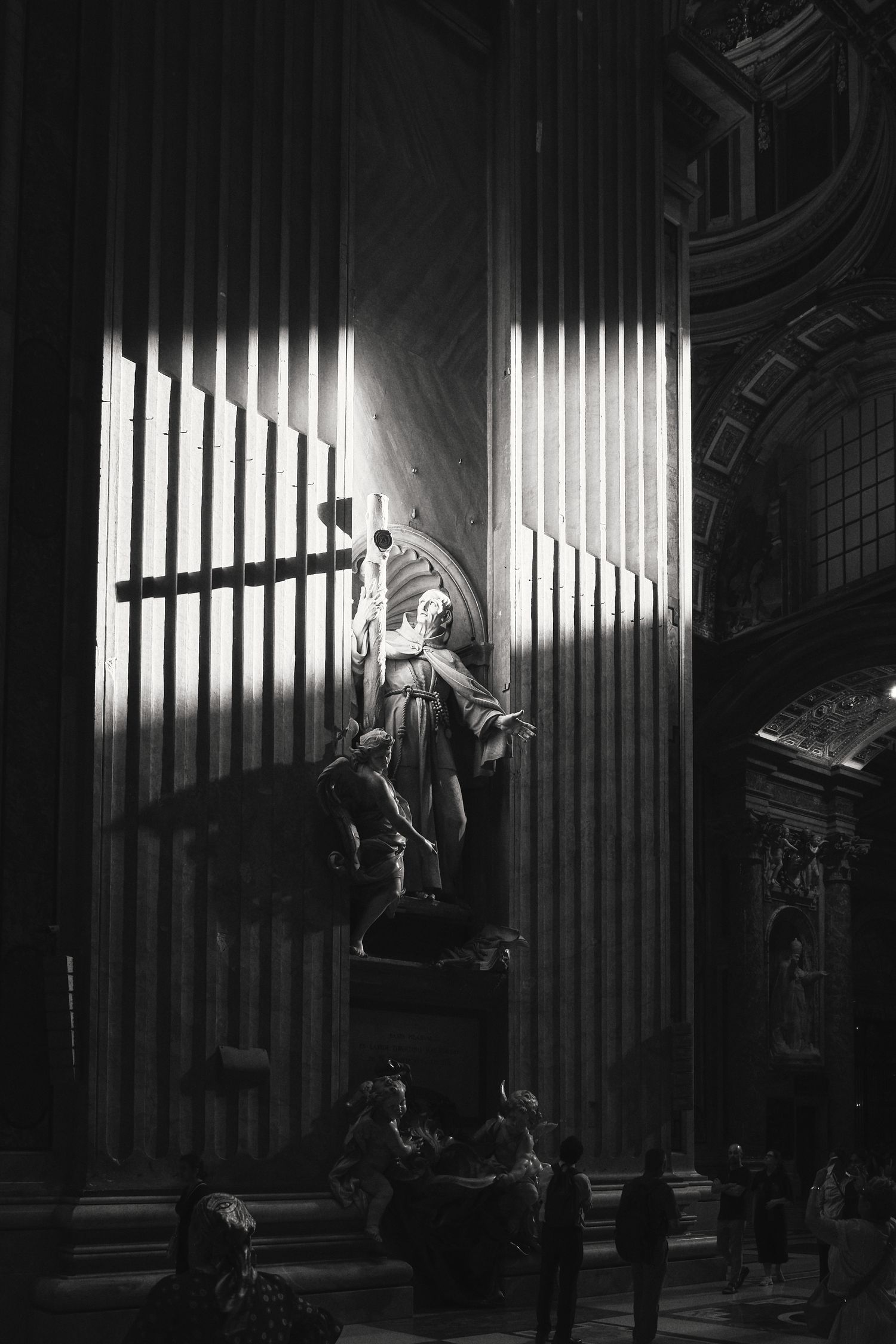 Dramatic black and white photograph of an angel statue among organ pipes in Saint Peter's Basilica.
