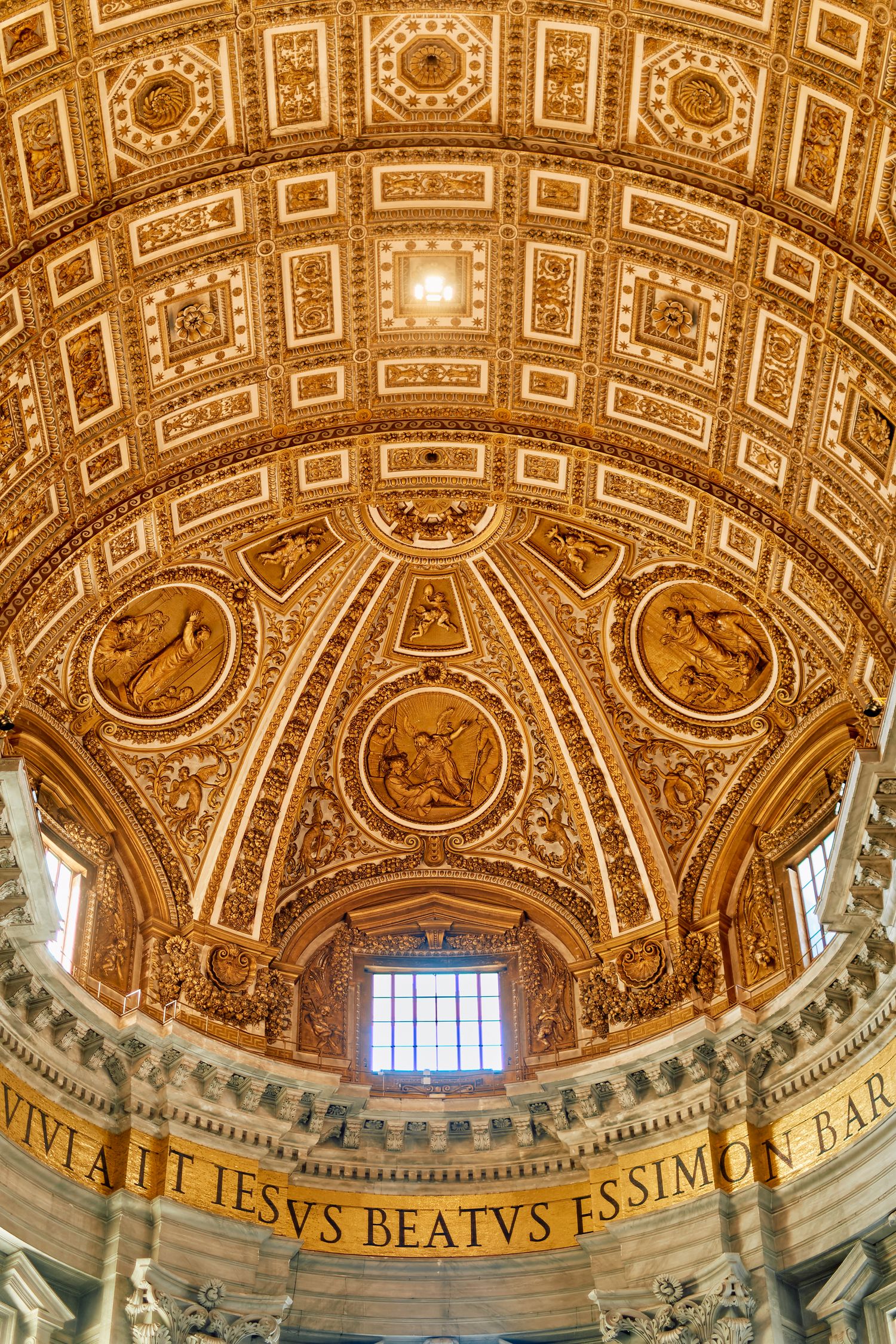 Golden decorated dome ceiling with religious medallions and Latin inscriptions in Saint Peter's Basilica.