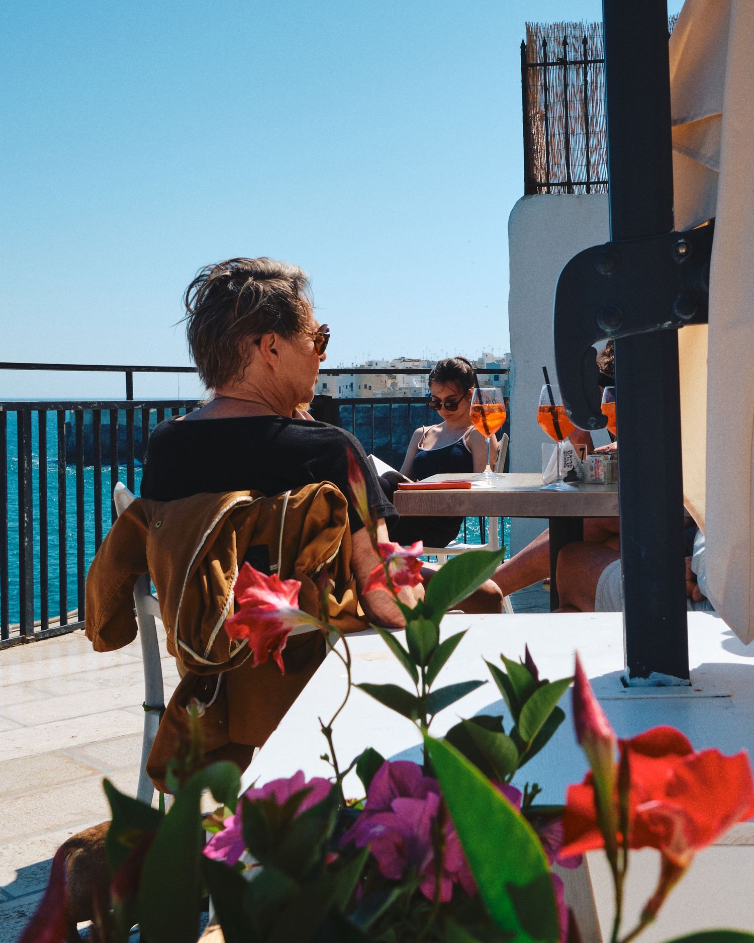 Seaside terrace with colorful flowers and ocean view seating.
