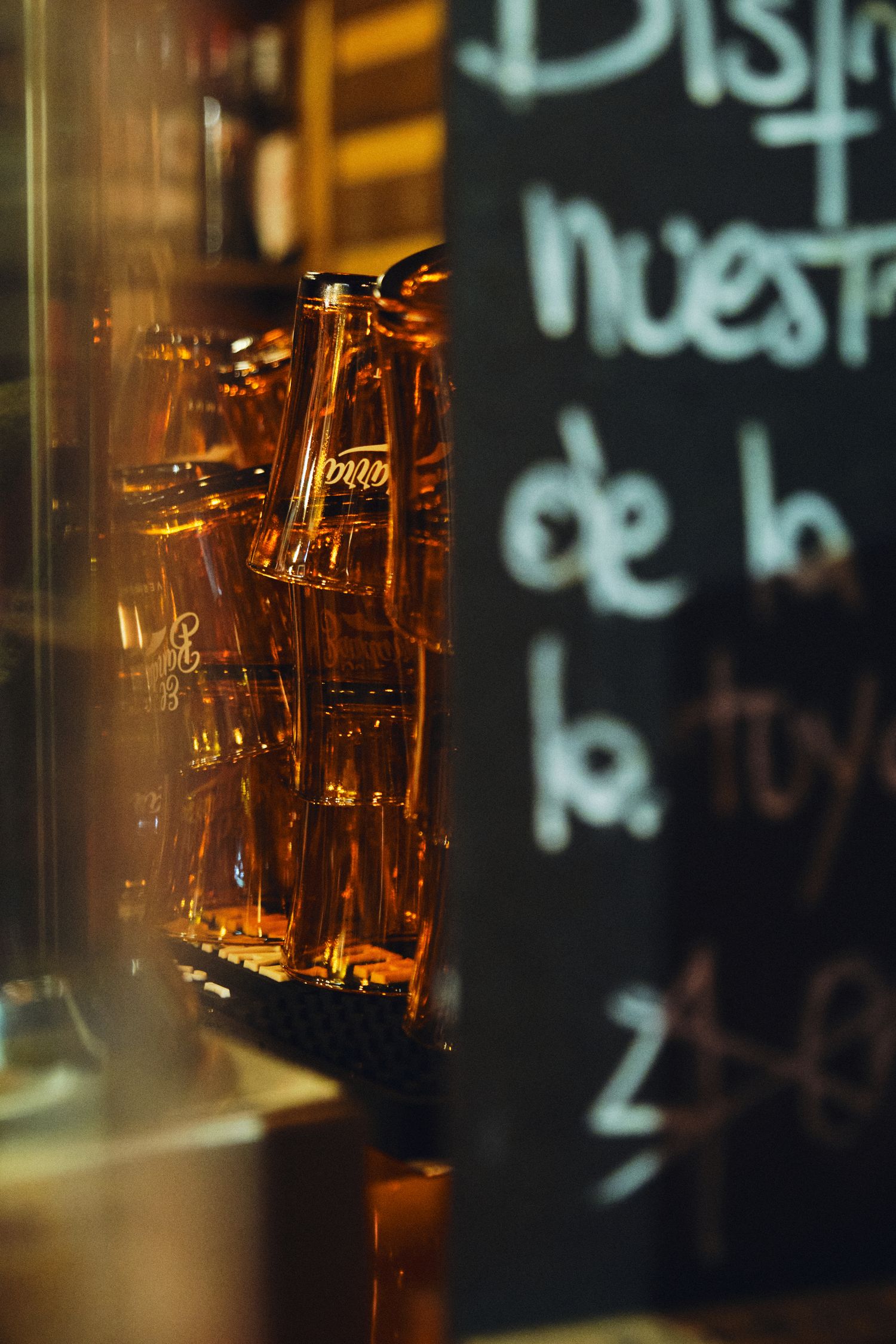 Amber bottles illuminated behind glass with a menu chalkboard in the background.
