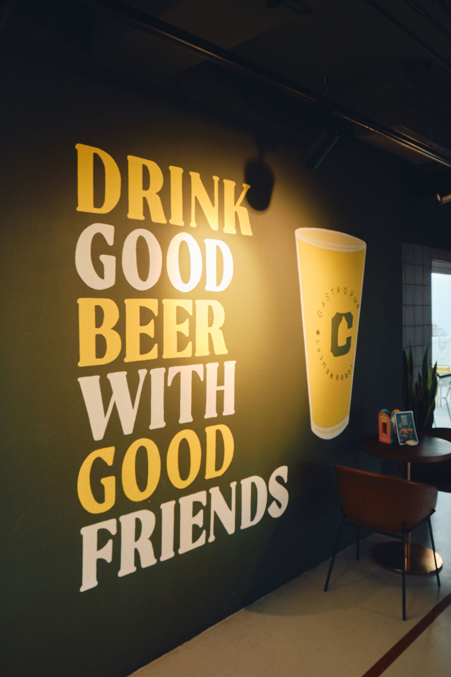 Motivational wall art about drinking beer with friends against dark background.
