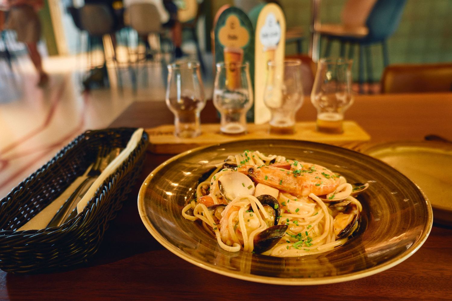 Plate of pasta with shrimp served with wine glasses in restaurant setting.
