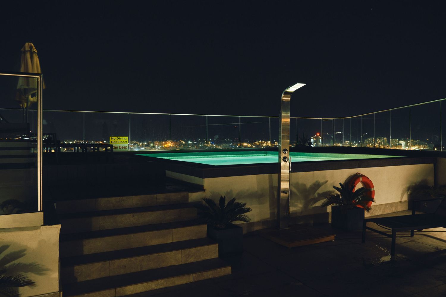 Nighttime terrace overlooking city lights with modern outdoor furniture.