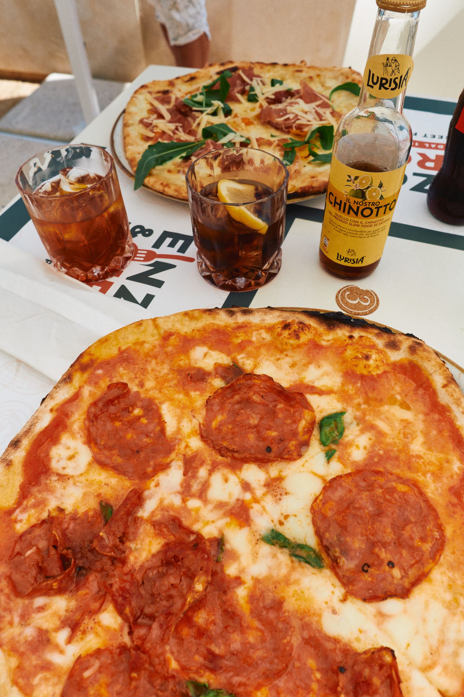 Pepperoni pizza and cocktails served with Minuty rose wine at an Italian restaurant.