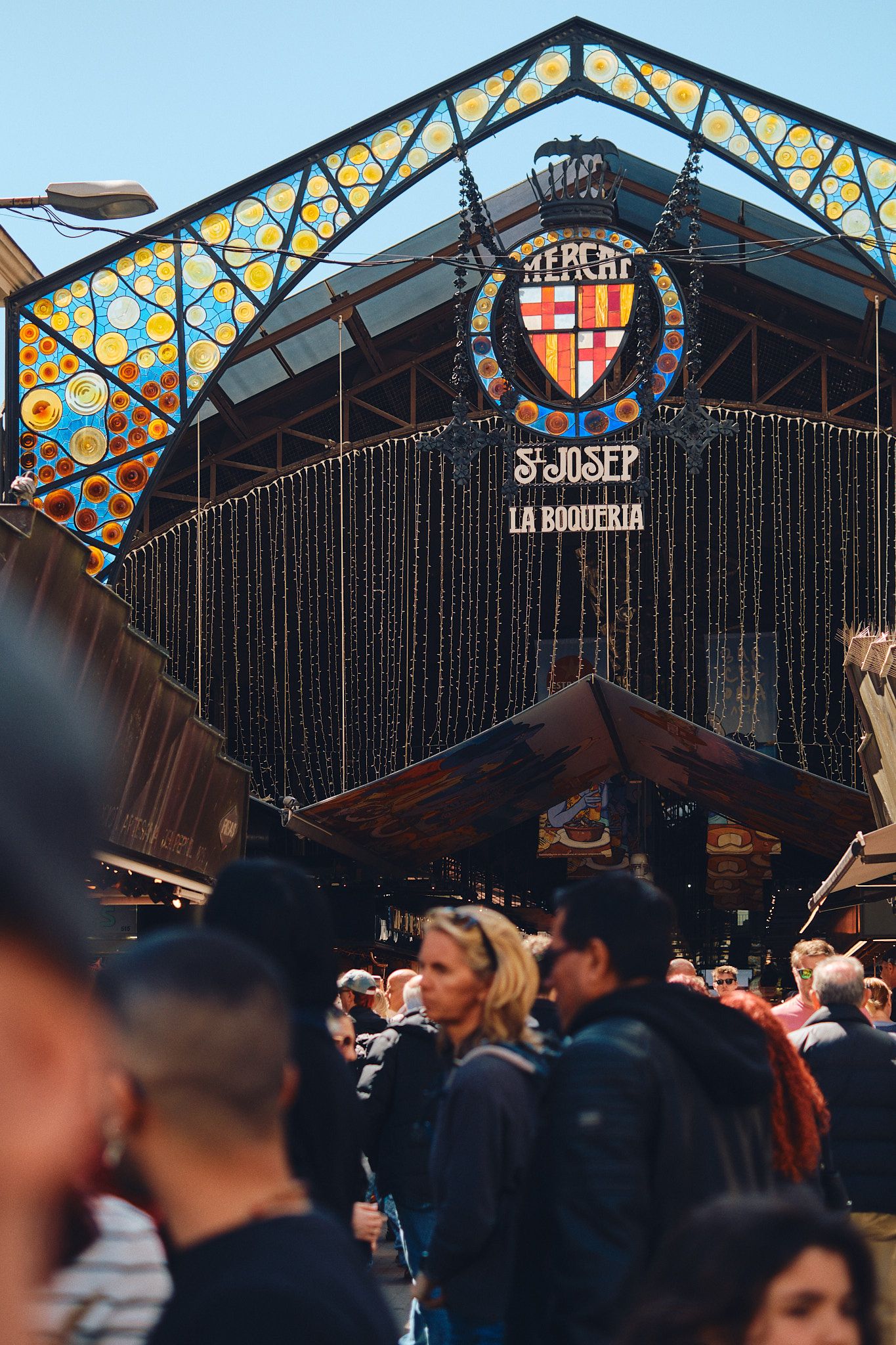 Crowded entrance to Mercat de Sant Josep de la Boqueria market in Barcelona, Spain, featuring colorful mosaic facade.