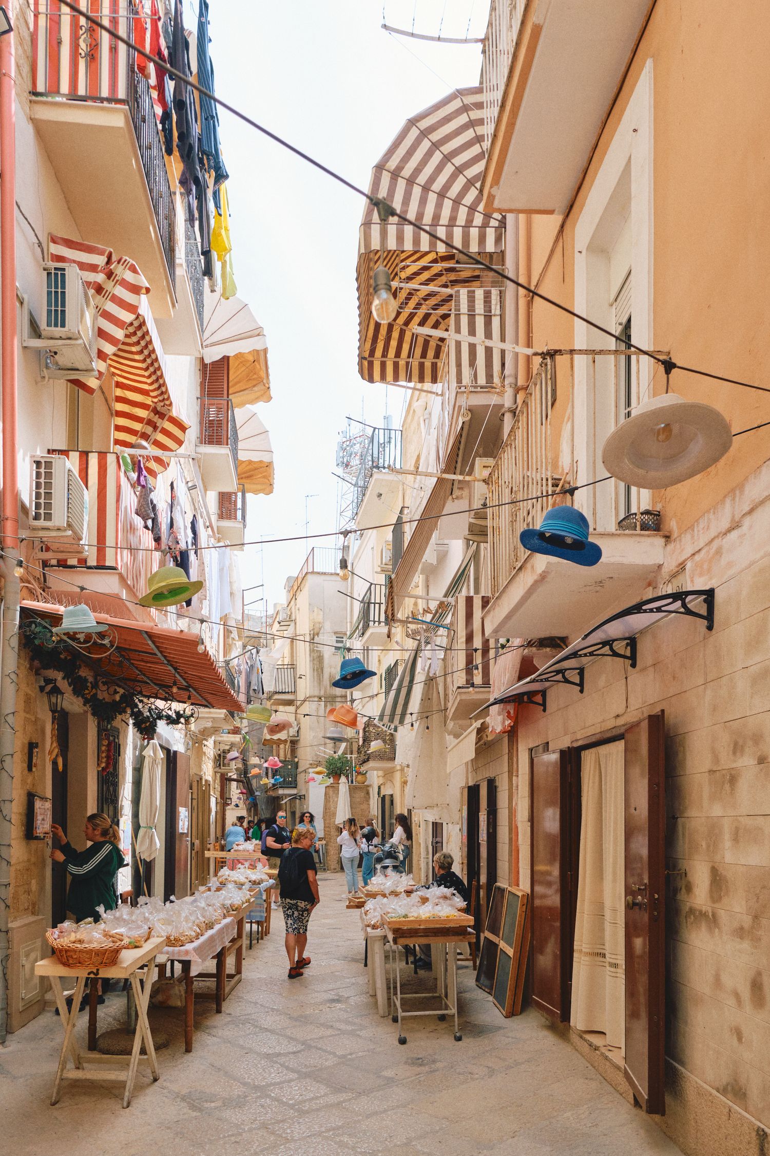 Charming Italian street with striped awnings and market stalls along stone buildings.