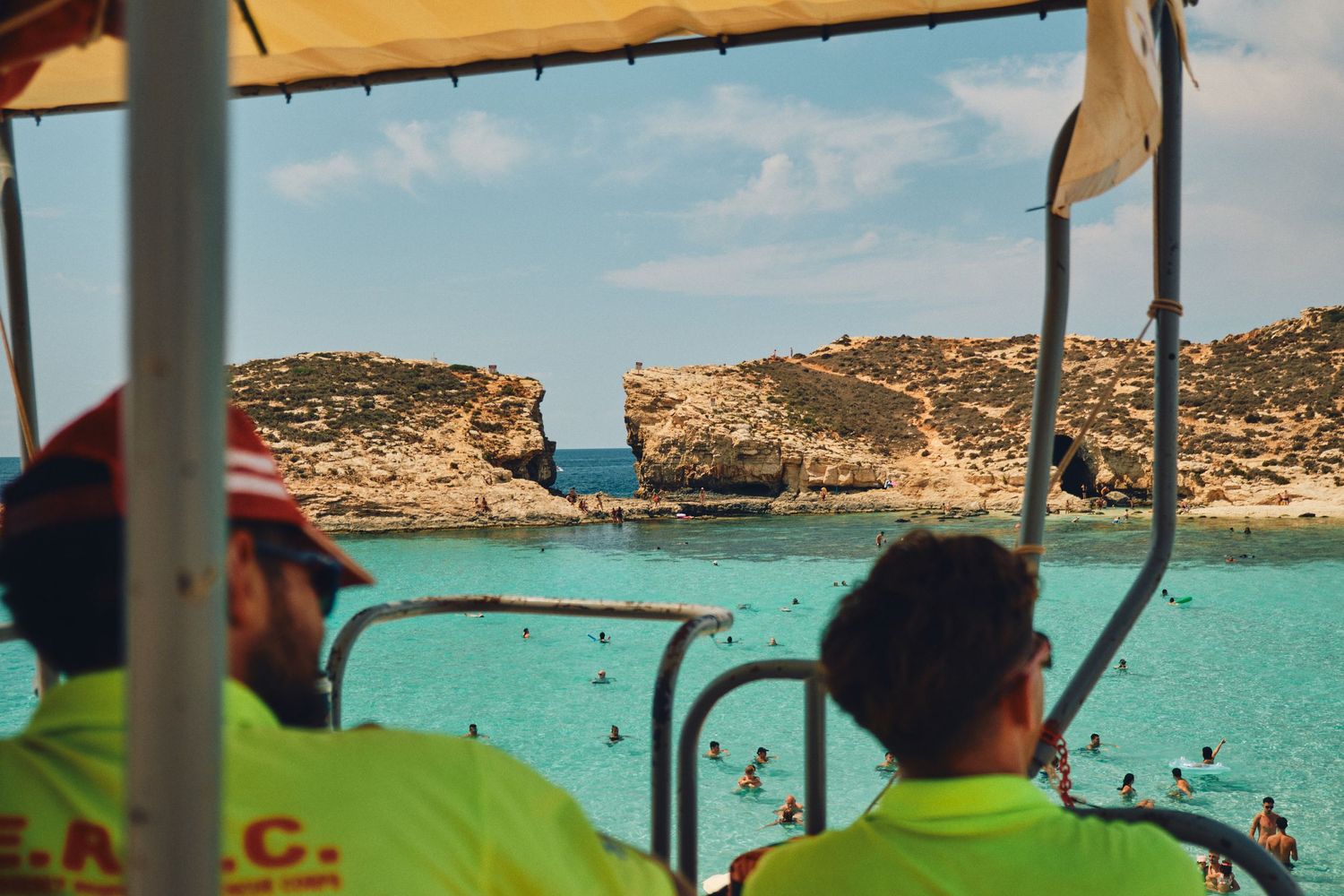 View through boat canopy of Malta's Blue Lagoon and rocky coastal cliffs.