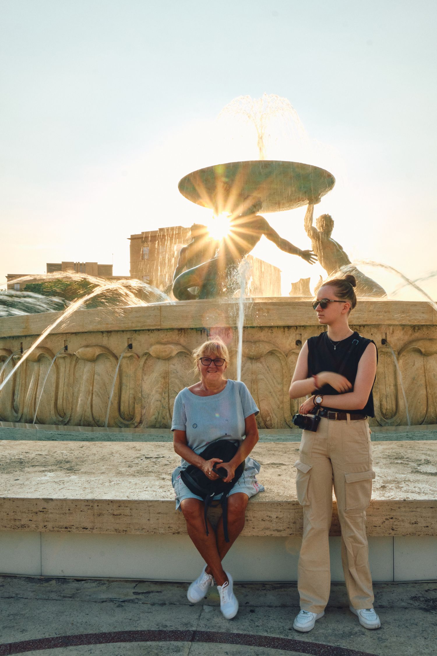 Sunburst through decorative fountain at sunset in Mediterranean city.