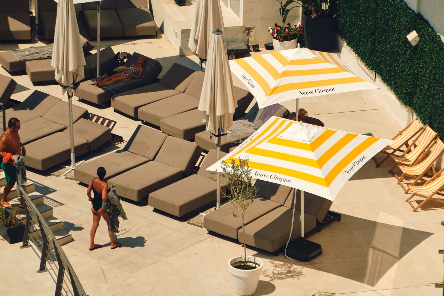 Yellow and white striped umbrellas shade lounge chairs by a pool area.