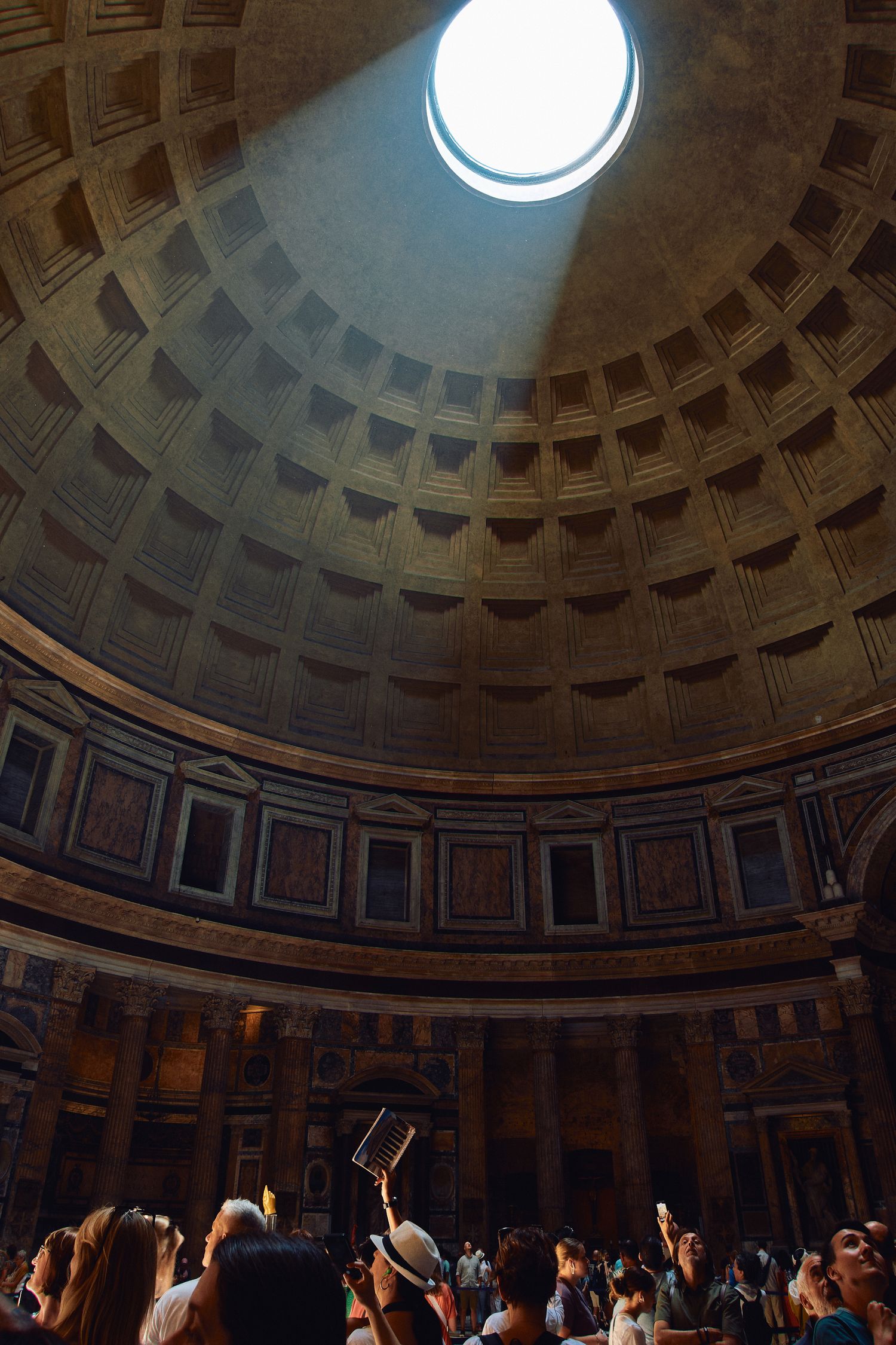 Sunlight streams through Pantheon's oculus as visitors gather in the historic rotunda.