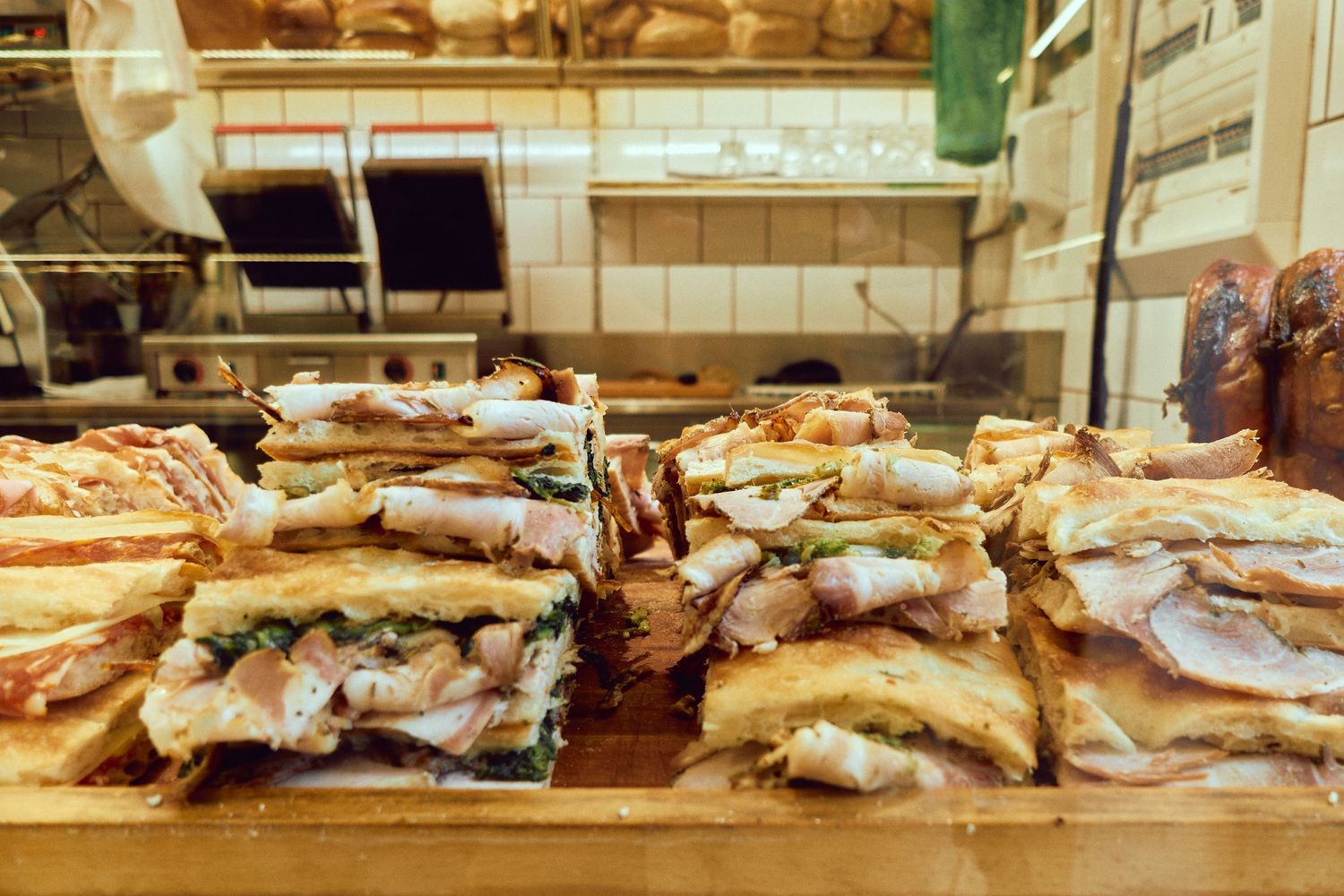 Fresh Italian sandwiches stacked on display at a local deli counter.