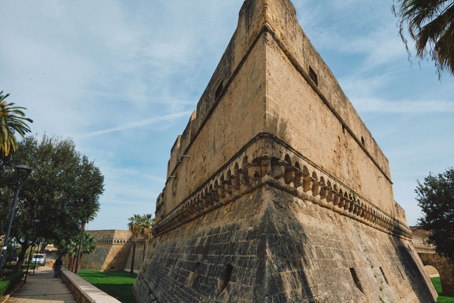 Imposing stone fortress wall with angular bastion corner against blue sky.