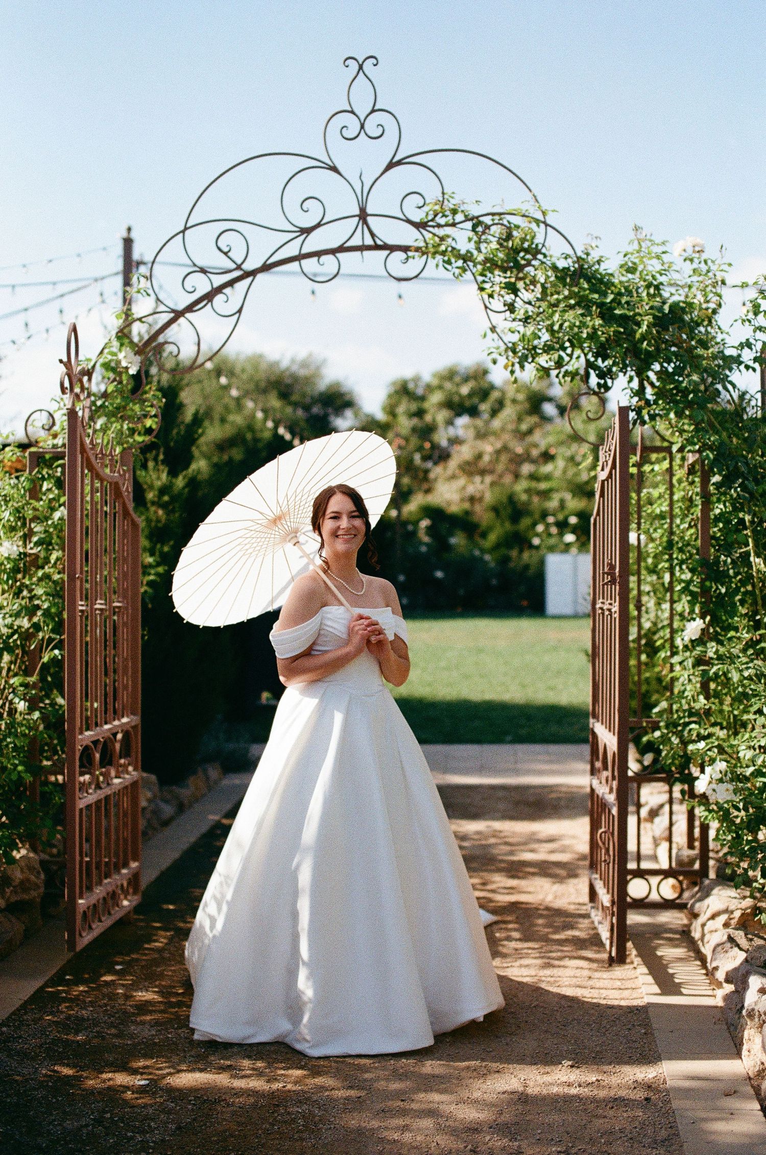 Bride poses with parasol at Tuscan Rose Ranch in Santa Paula California.