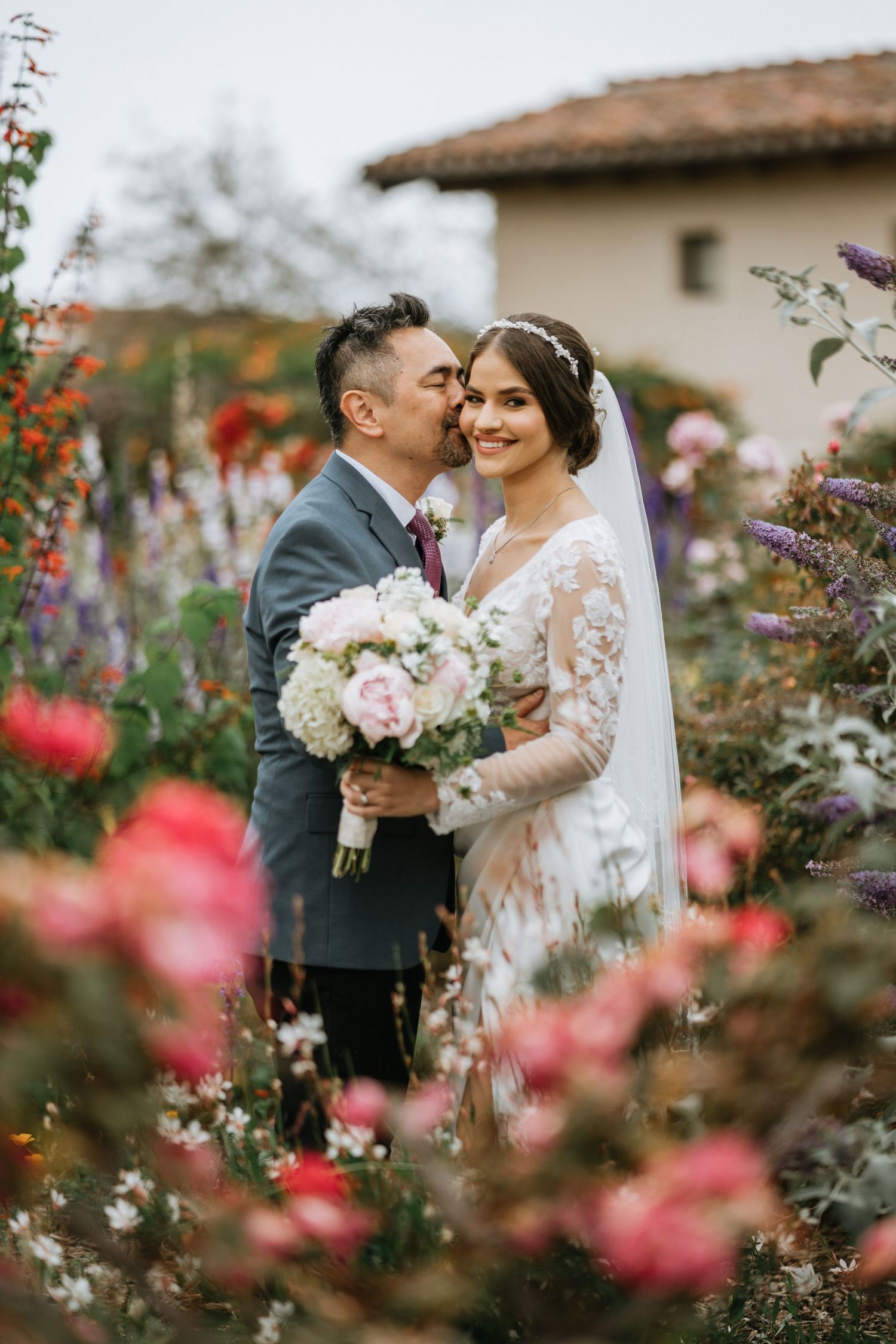 Bride and groom share a kiss in the courtyard of Mission San Juan Capistrano in San Juan Capistrano, California.