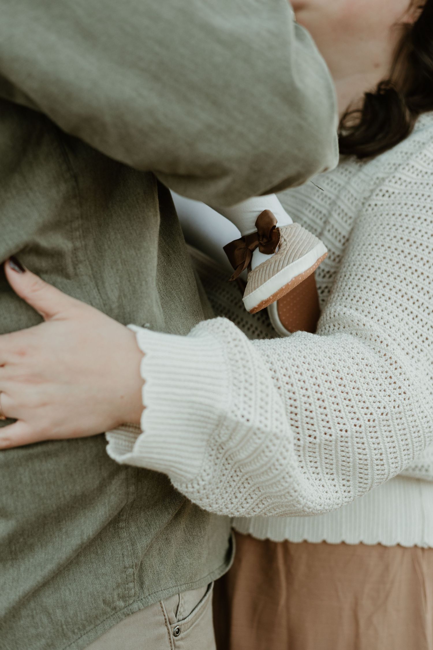 Close-up details of white knit sweater and olive jacket during an intimate moment.