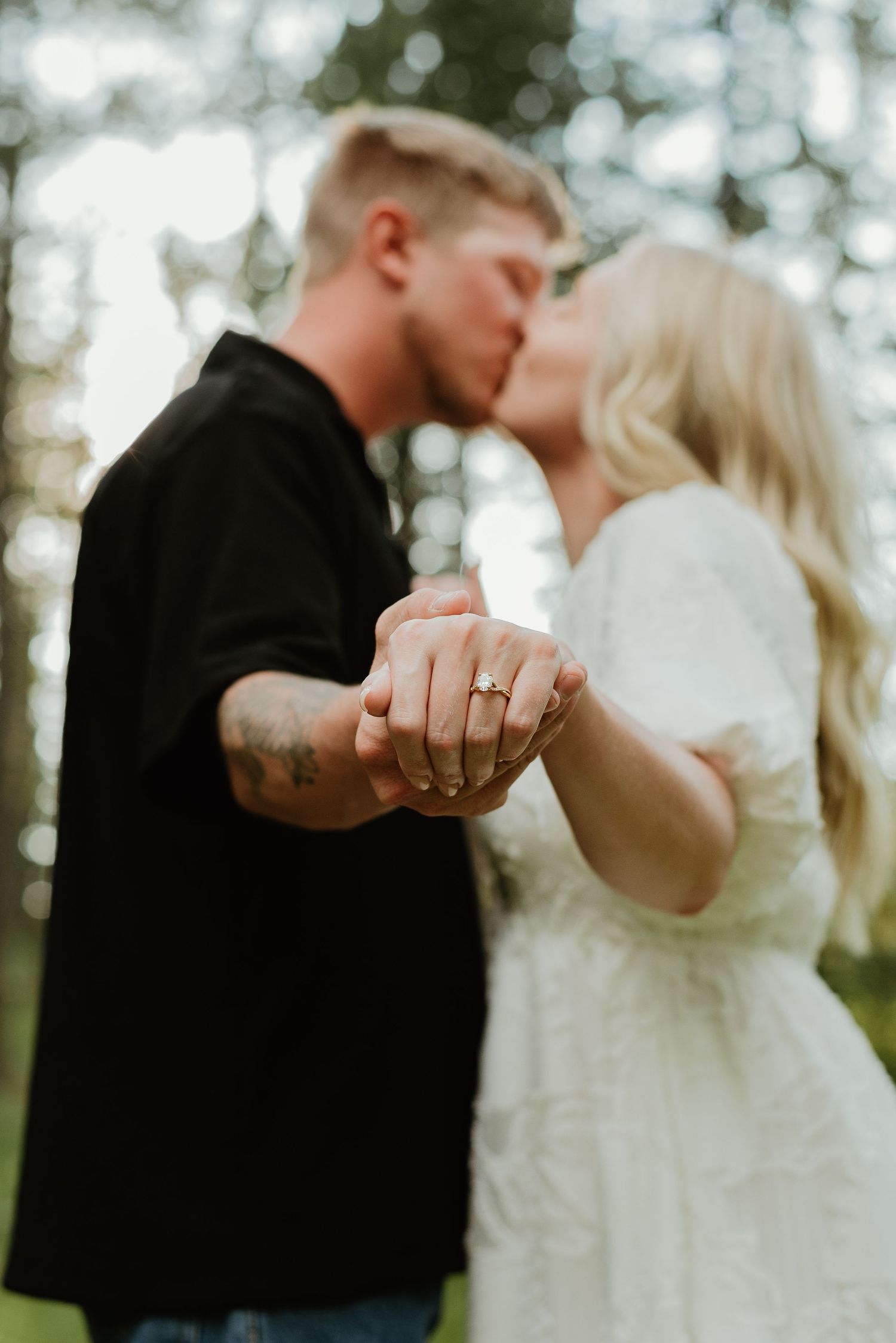 Romantic outdoor wedding portrait showing couple kissing in forest setting.