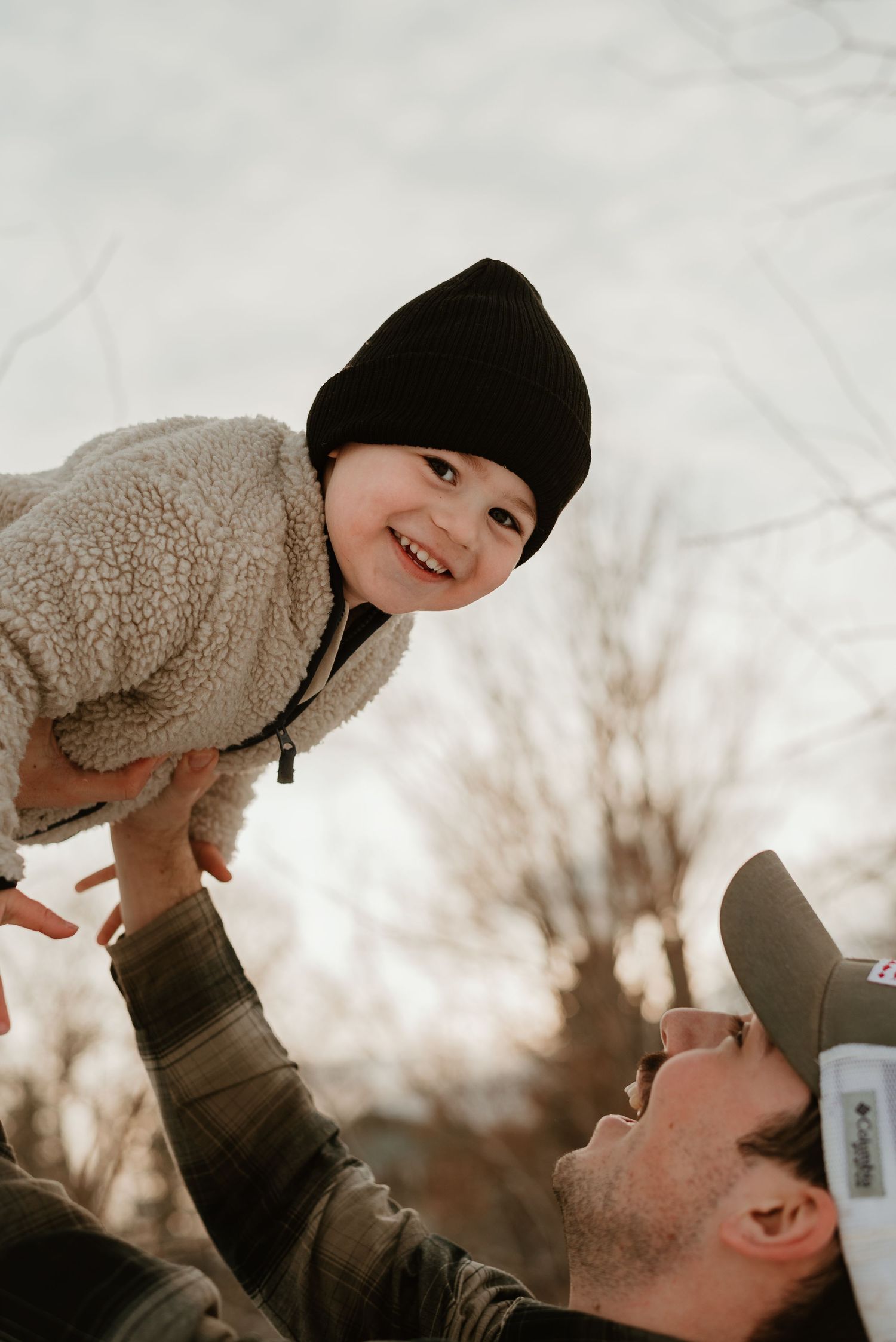 A playful winter moment between parent and child wearing warm clothing against a snowy backdrop.