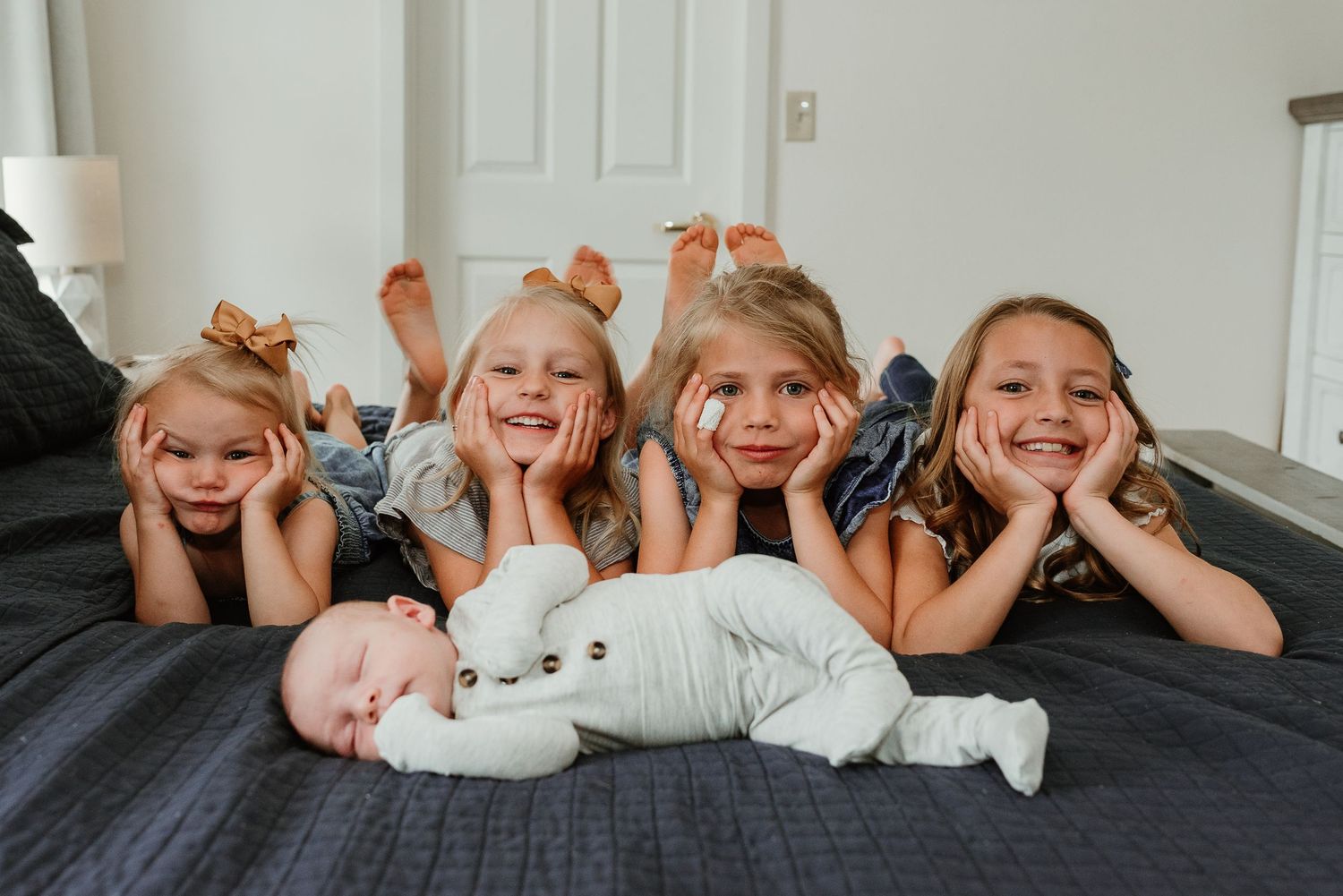 Children lie in a row on a bed making silly faces.