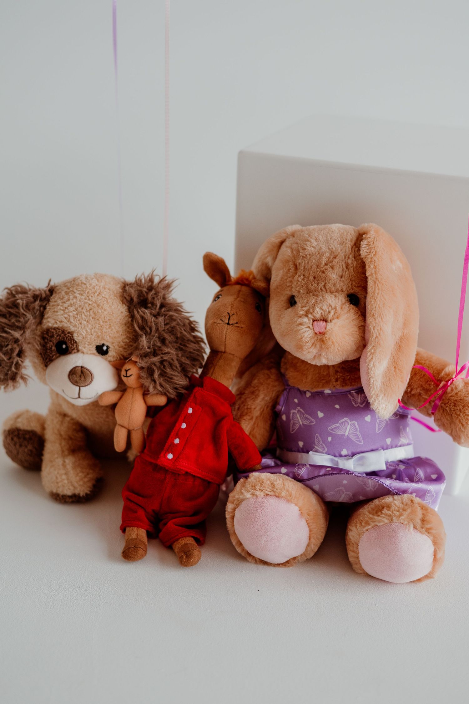 A row of adorable plush teddy bears and stuffed animals arranged in a line against a white background.