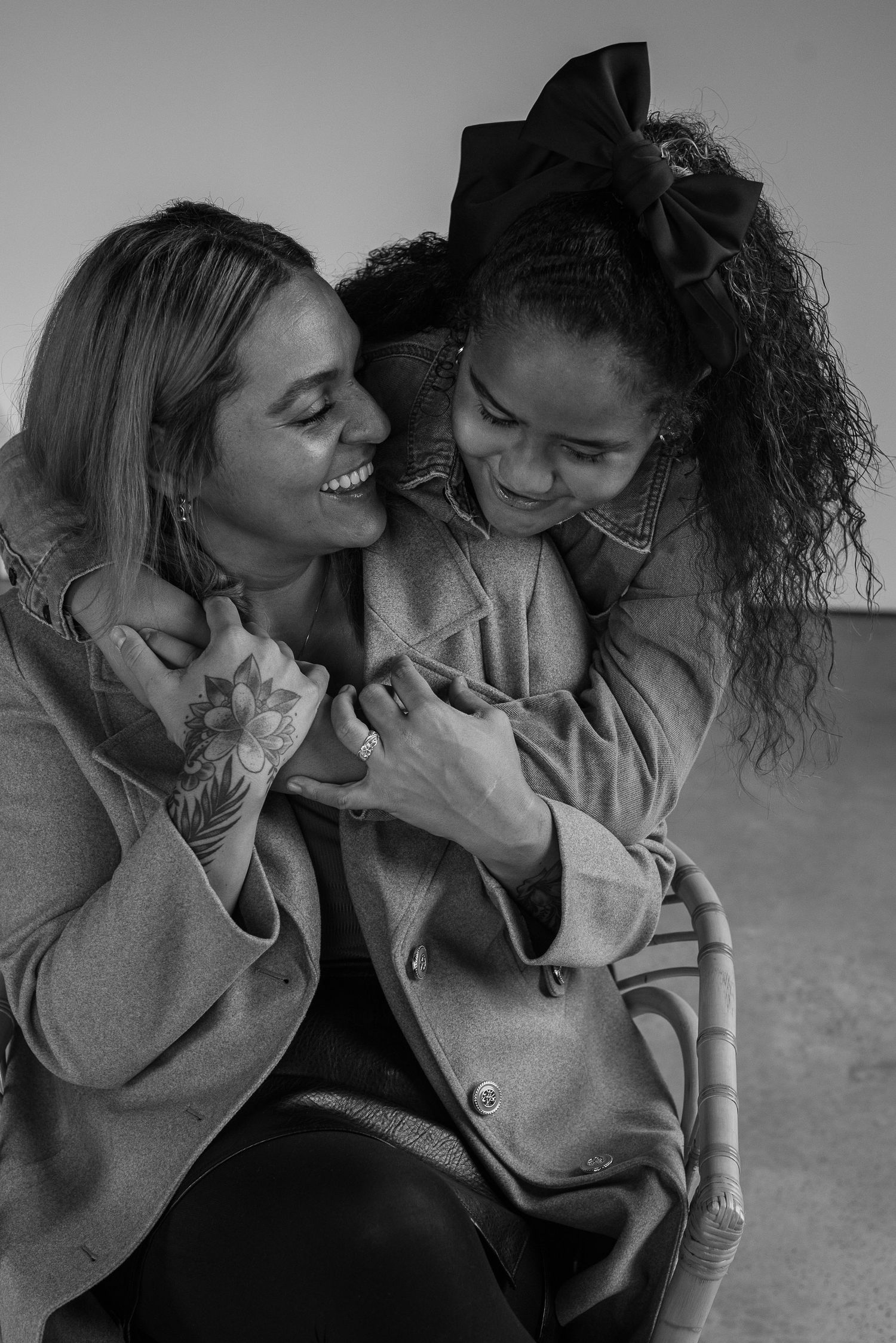 Two friends sharing joyful laughter while embracing in black and white portrait.