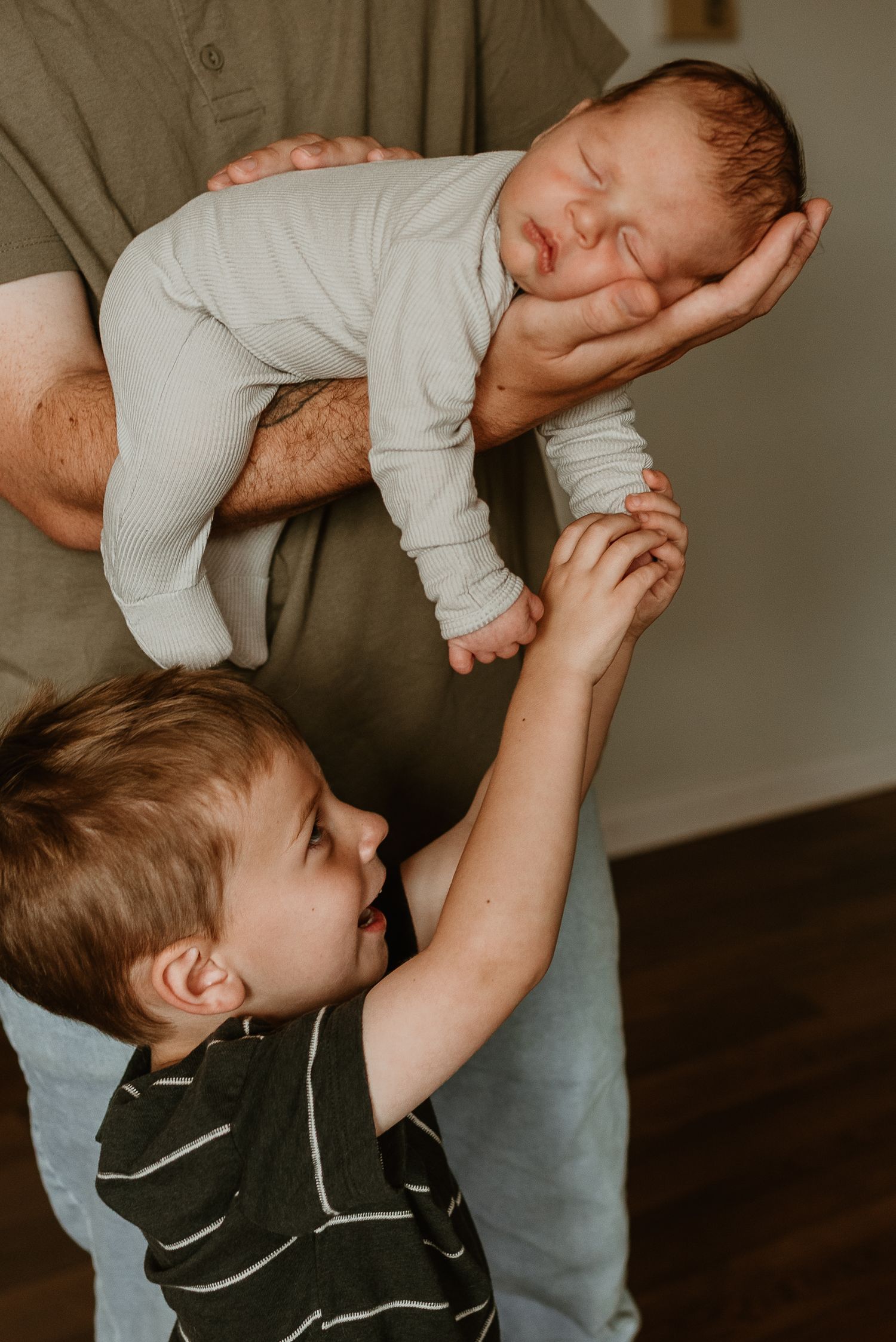 A sequence of photos showing a child lifting a baby in a white onesie, displaying playful interaction between siblings.