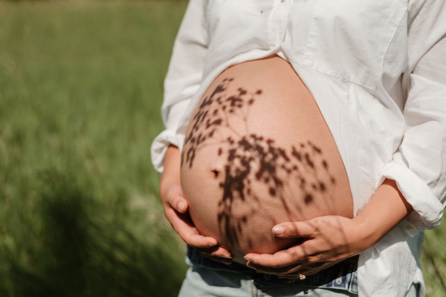 Artistic maternity photos showing sunlight patterns on pregnant belly.