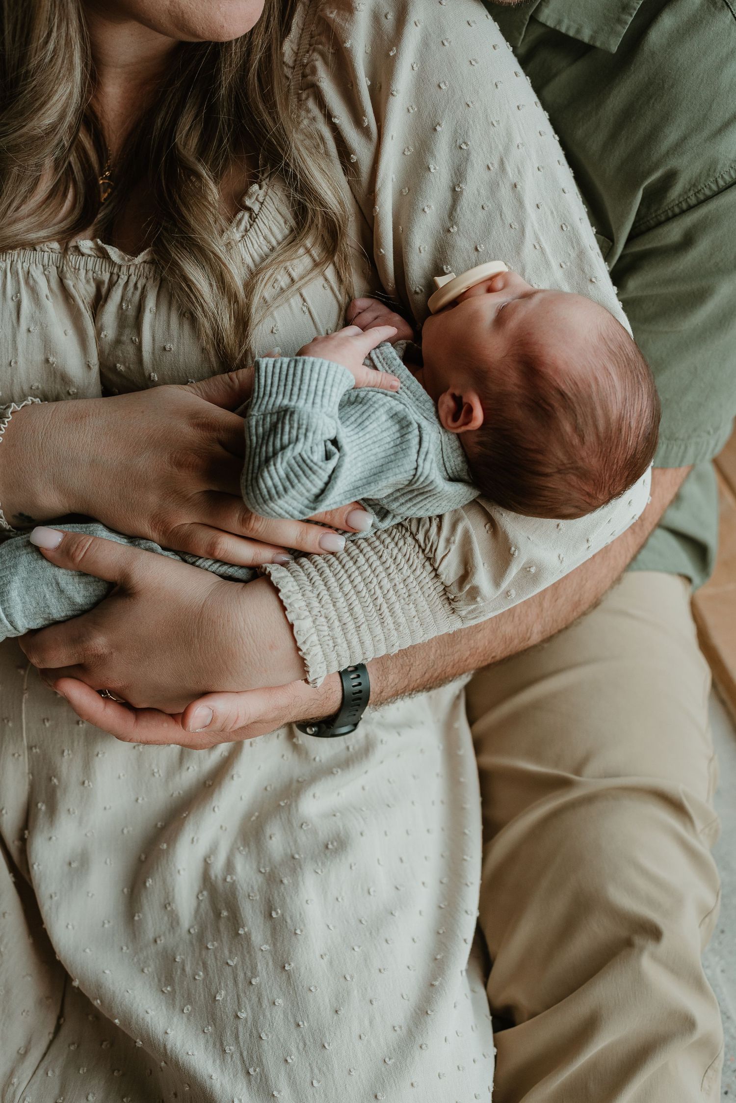 Intimate family photos showing gentle moments with a newborn baby in soft lighting.