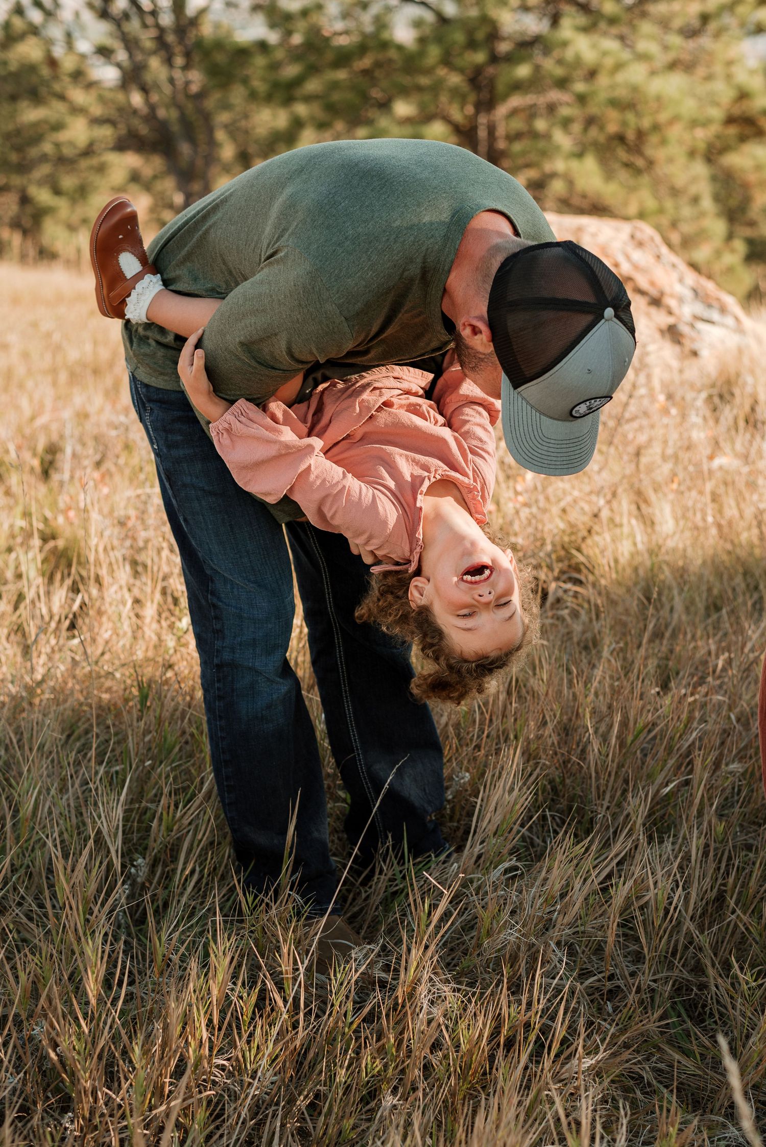 A playful sequence of someone being dipped backwards while laughing in a grassy field at sunset.