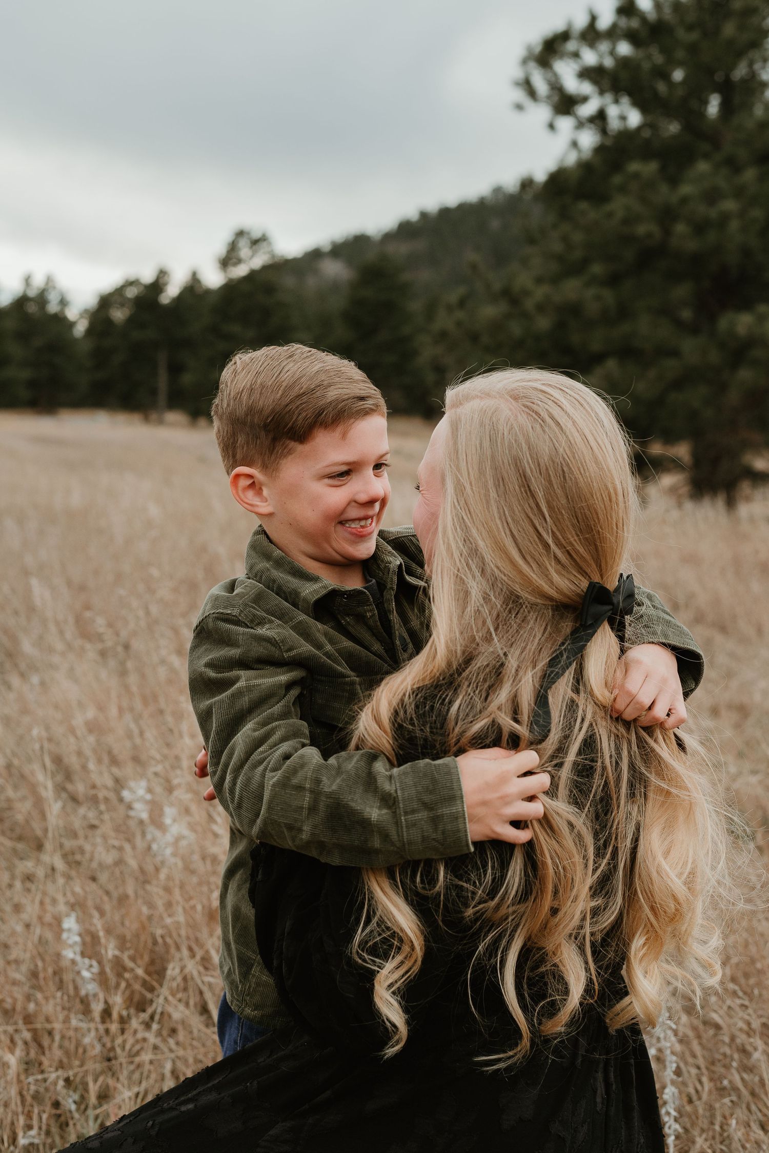 Playful candid moments between a couple in a golden field with mountains in the distance.