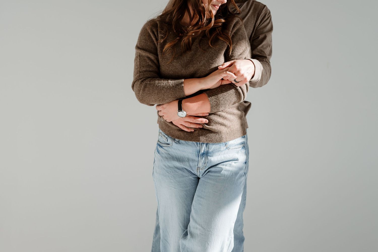 Casual lifestyle portrait showing cropped view of person in denim and neutral tones.