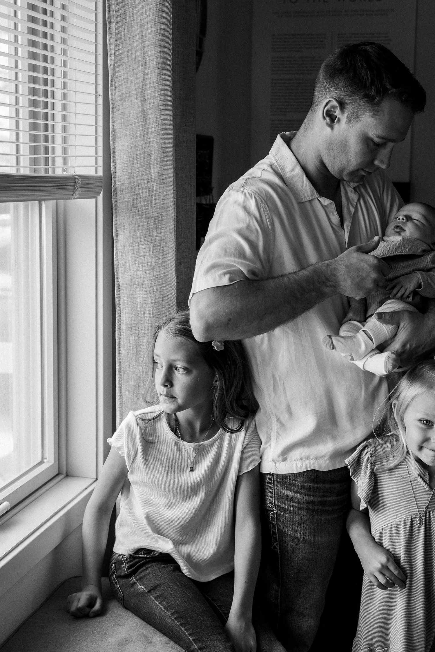Black and white portrait series showing intimate moments between family members near a window.