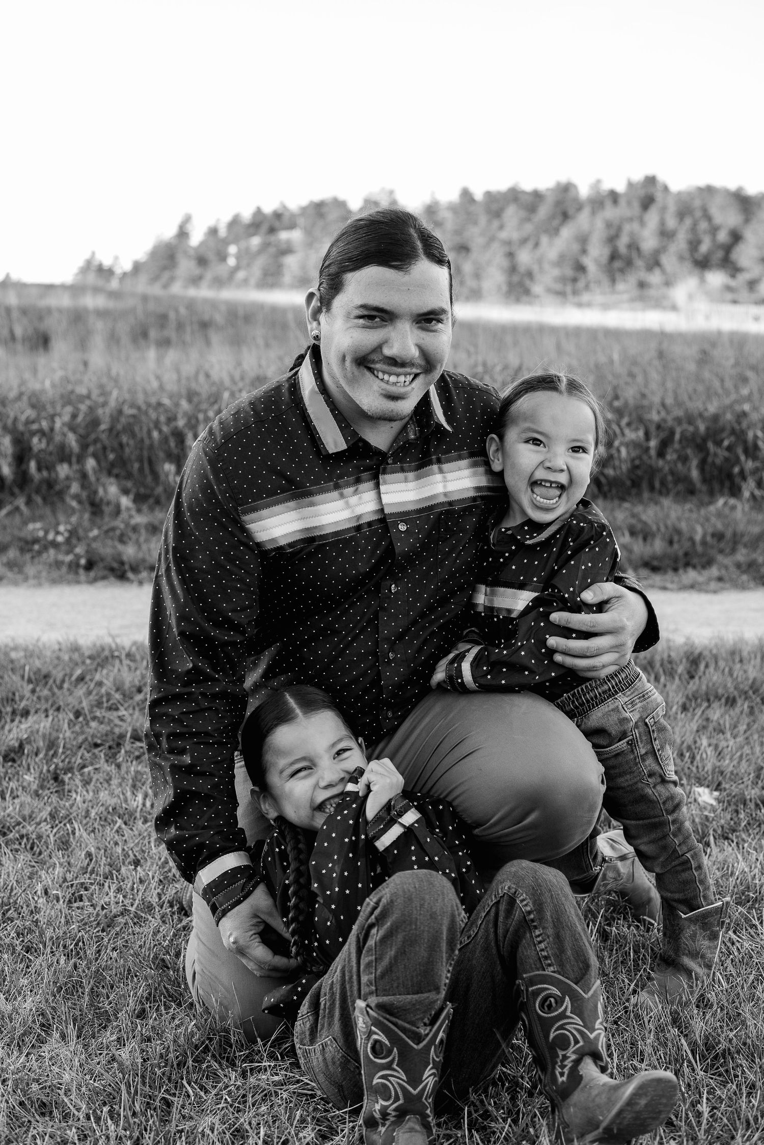A joyful outdoor family portrait with laughter and matching outfits in a field setting.