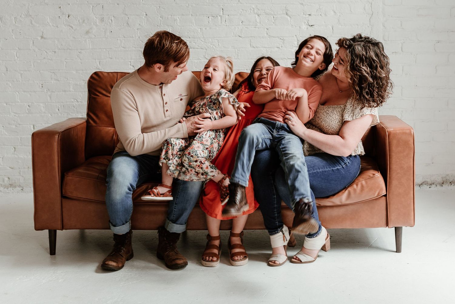 Family lounging together on brown leather couch.