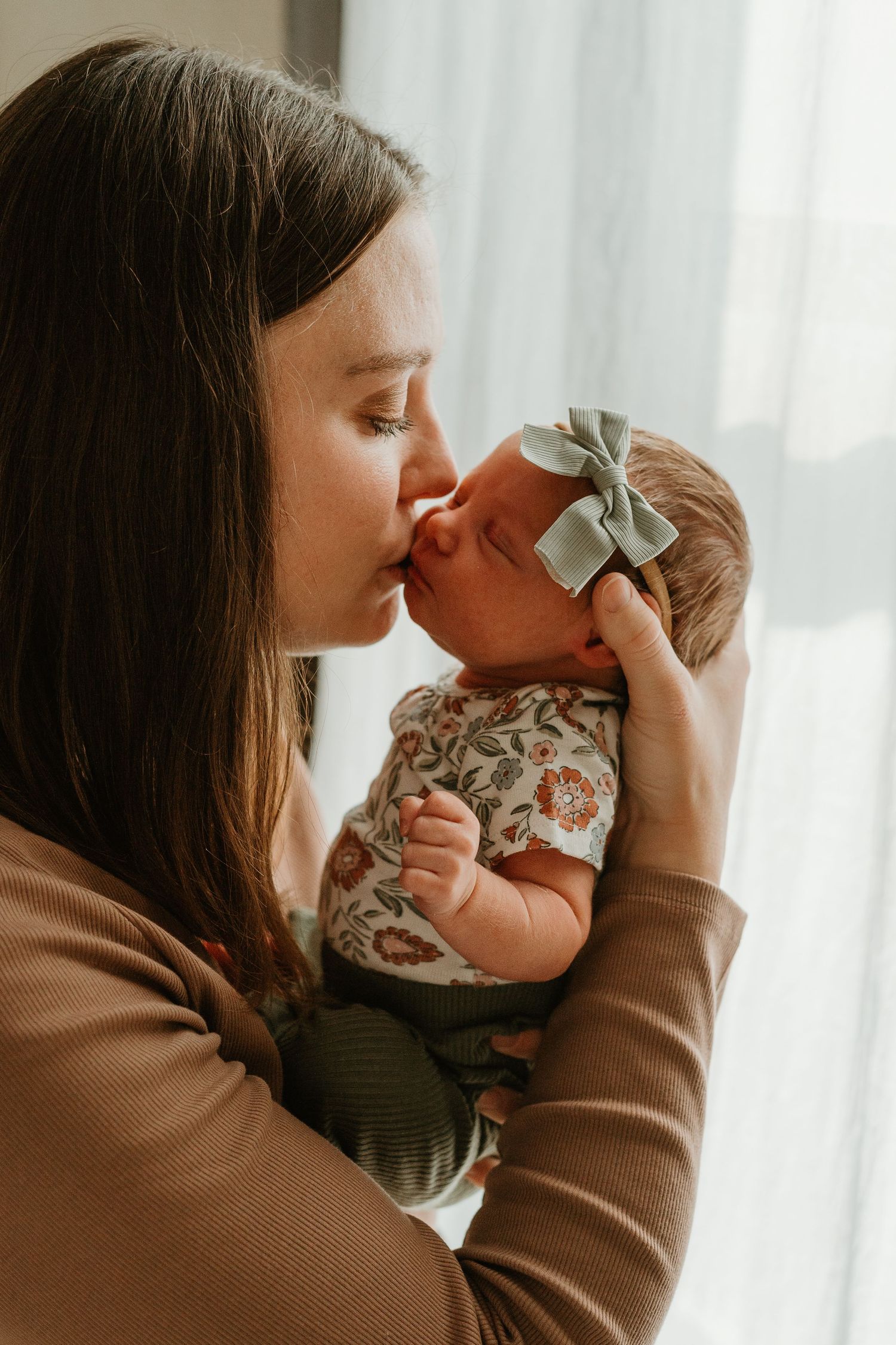 A tender moment between parent and infant shown in a series of warm-toned photographs by a window.