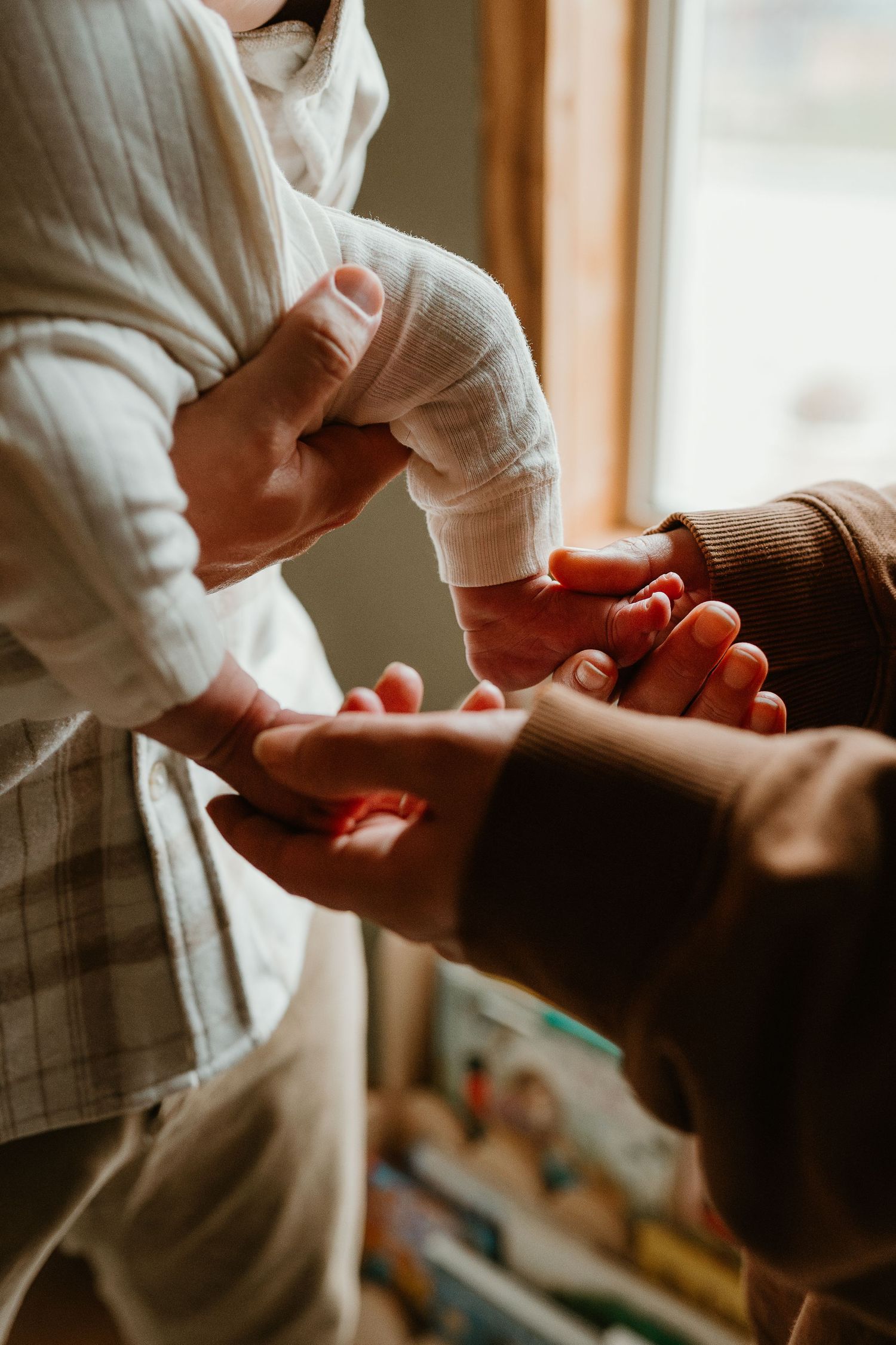 Close-up shots of hands gently touching and connecting in natural window light.