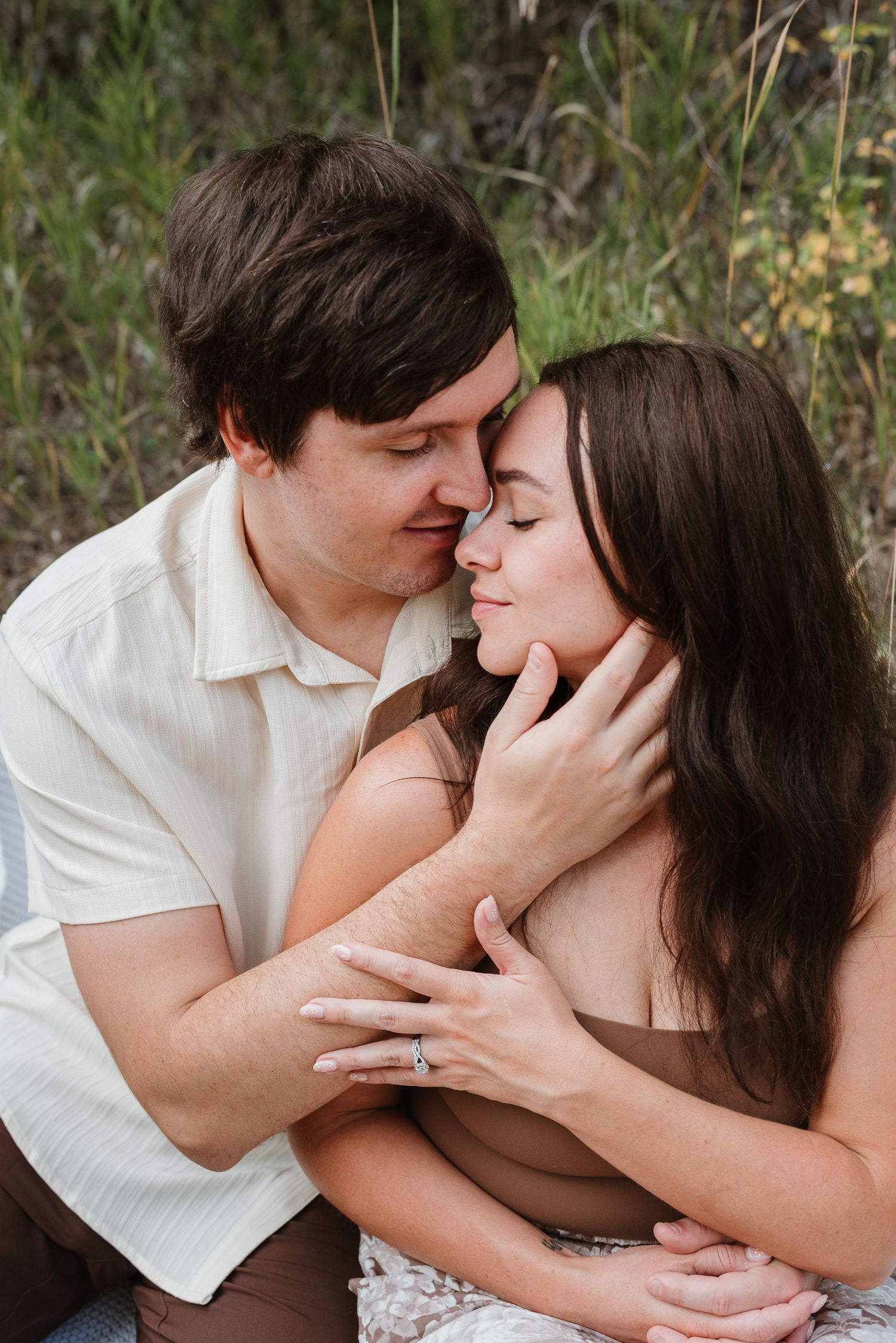 A romantic couple shares an intimate kiss outdoors while wearing white and black clothing.
