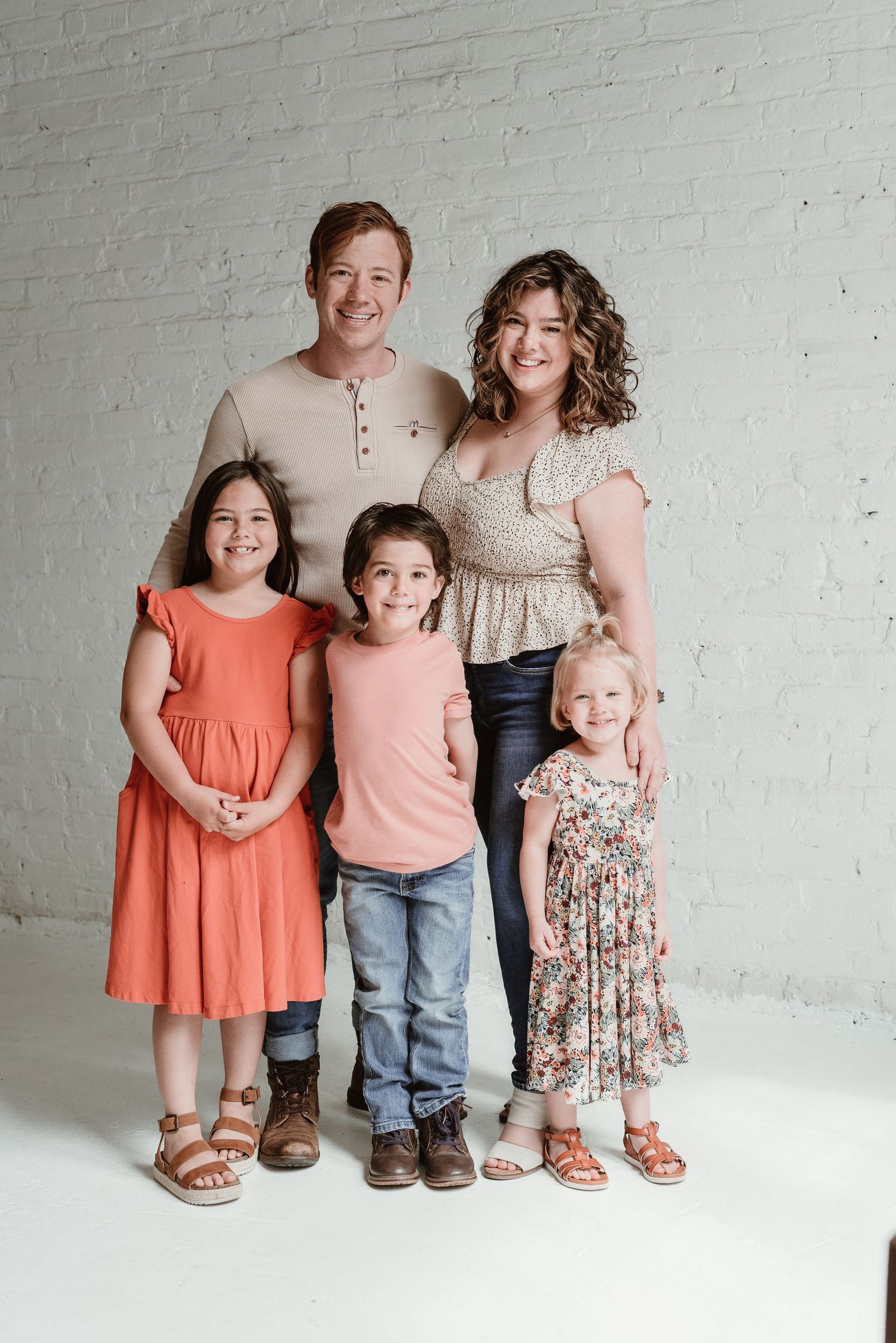 Family portrait series showing coordinated outfits in coral and neutral tones against a white backdrop.