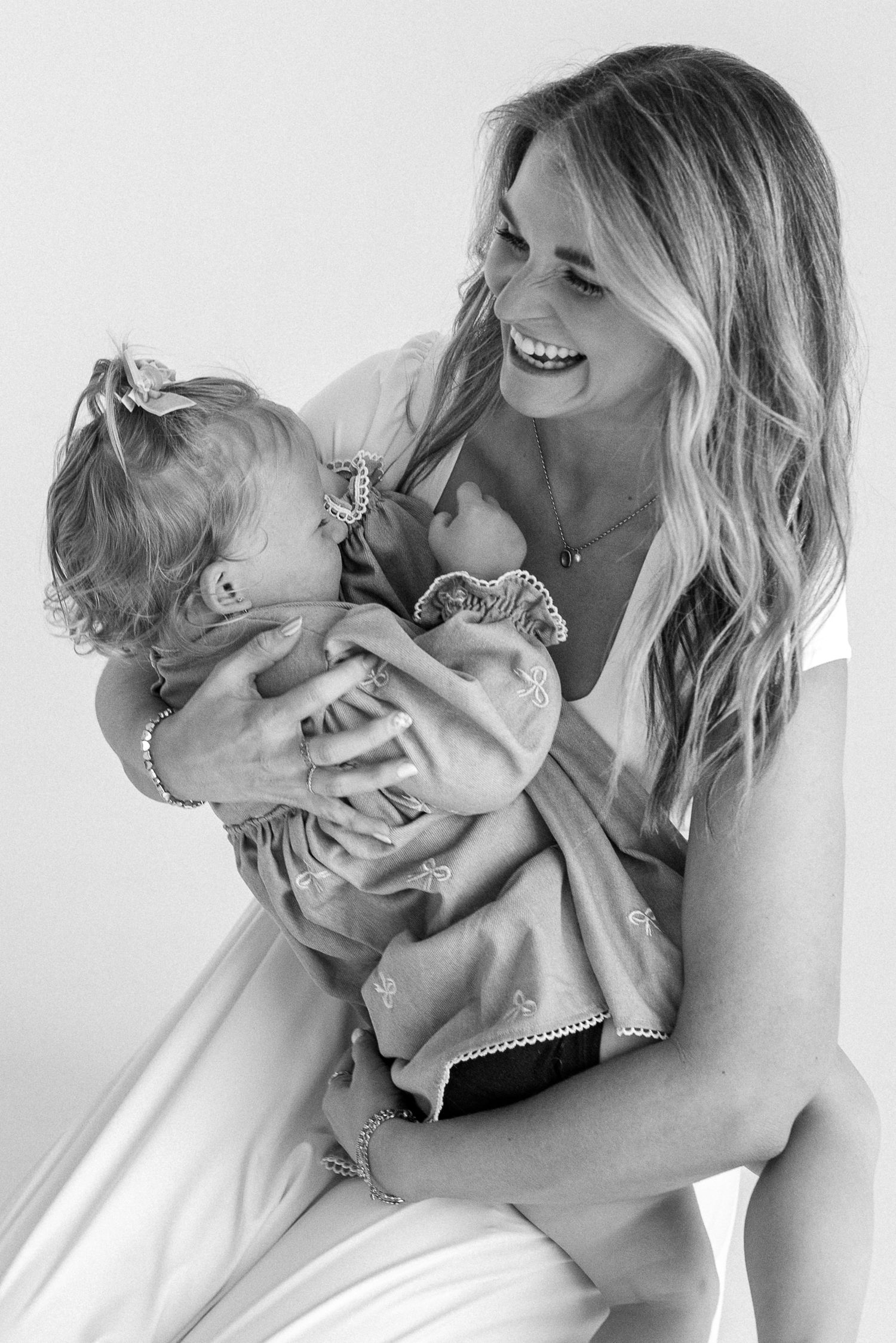 A series of black and white photographs showing a tender moment between parent and child in matching light outfits.