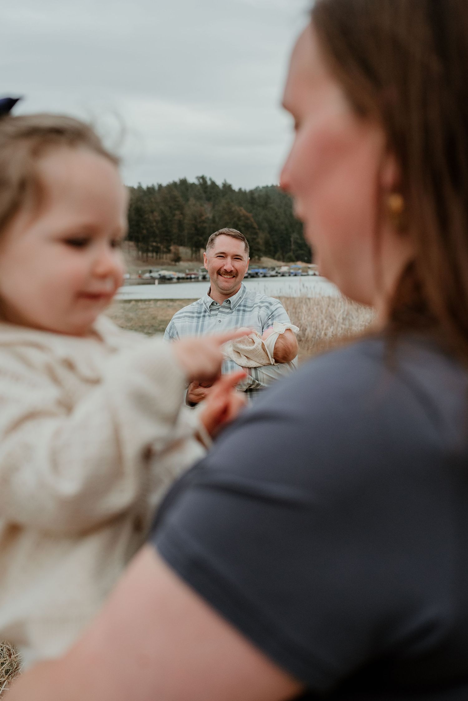 A candid family moment captured outdoors with mountains in the background.