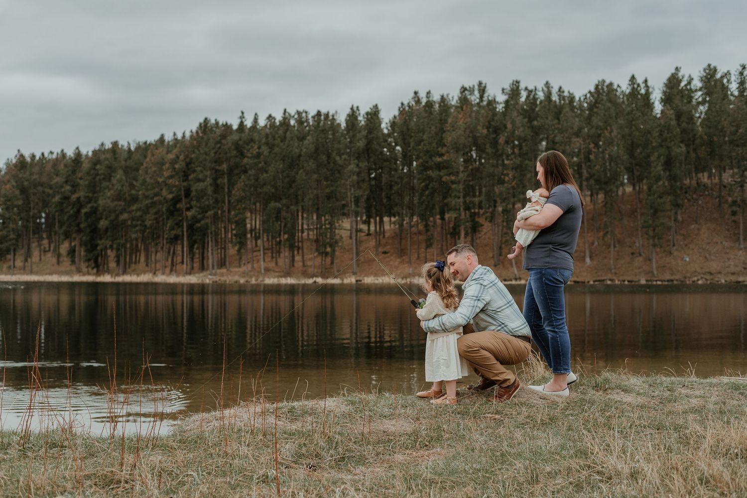 A family shares a special moment by a tranquil lake surrounded by pine forest.