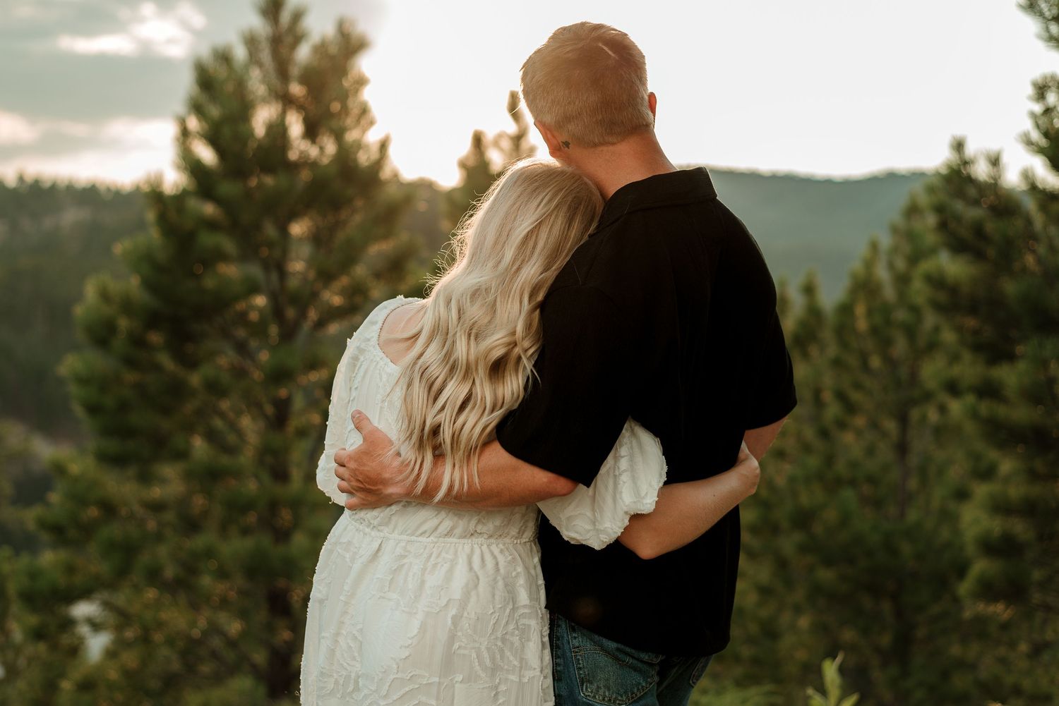 Couple embracing while enjoying a sunset view overlooking mountain landscapes.