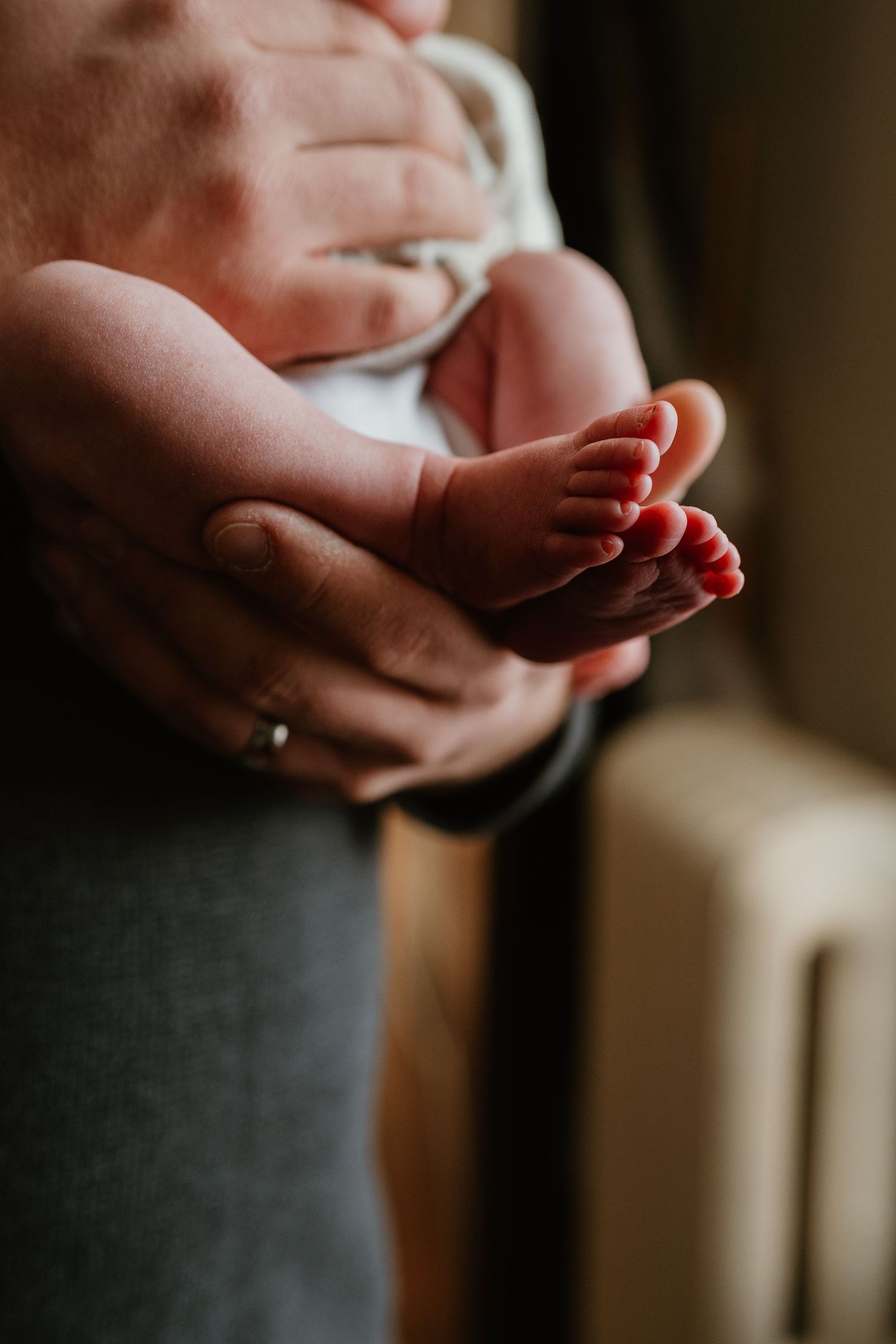 Close-up shot of tiny baby feet being gently cradled in adult hands.